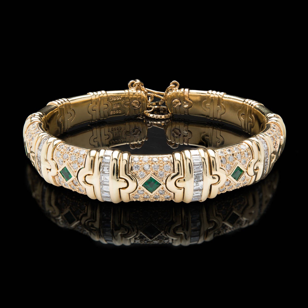 18Kt Yellow Gold Cuff Bracelet Features 5 Square Cut Emeralds totaling 0.60 carat total weight. Round brilliant & Asscher cut diamonds accent this piece with an approximate total of 3.61 carat weight. The bracelet measures 2.5 inches wide and 7