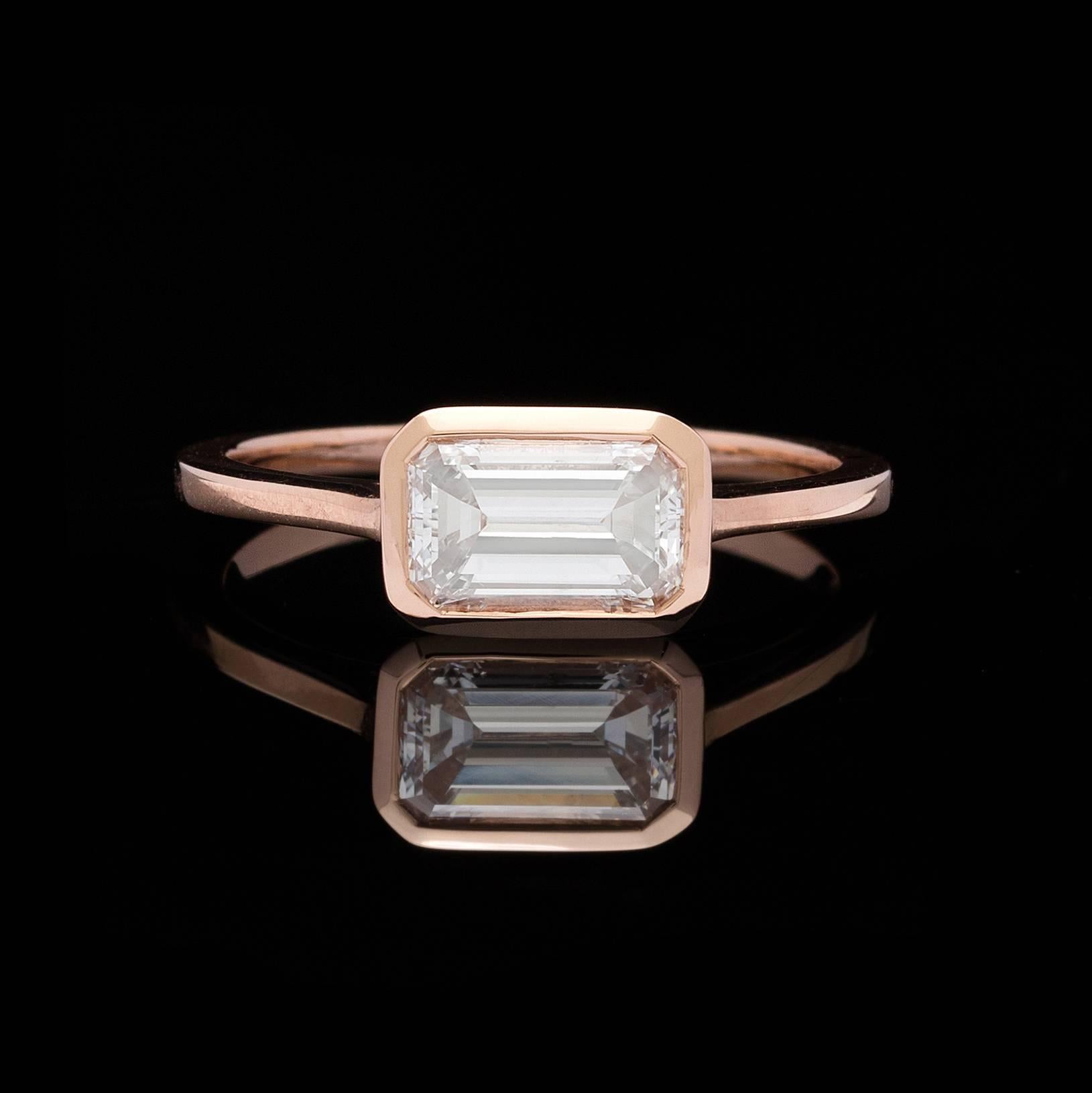 This contemporary, horizontally-set 1.02 carat emerald-cut diamond is set in 18k rose gold. Currently the ring is size 6 1/2, and can be adjusted up or down, weighs 2.2 grams, with a delicate band width of 1.3mm. This is a modern yet classic design.