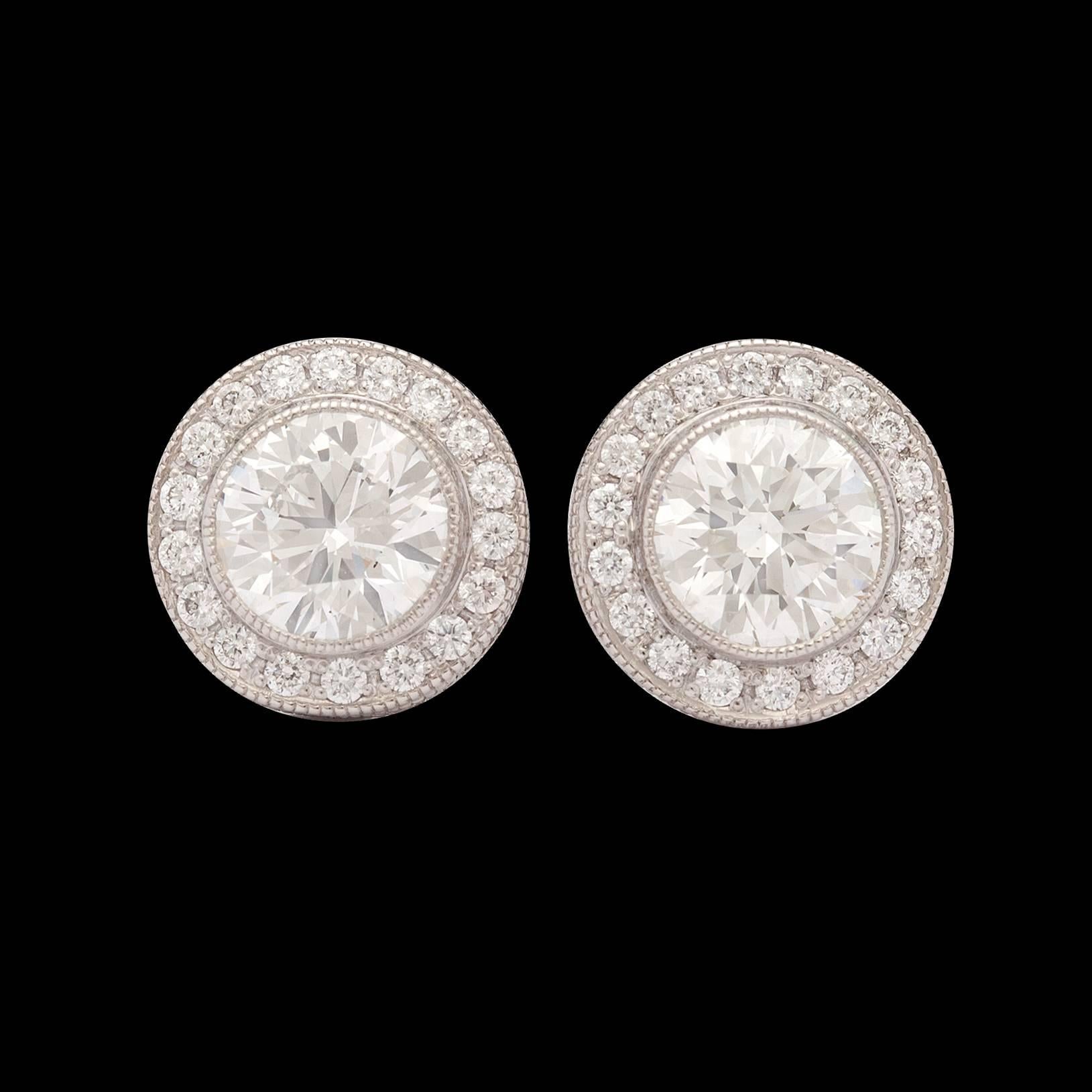 Platinum earrings feature two round brilliant cut diamonds weighing 1.60cttw bezel set in halos.  The additional 36 diamonds total approximately 0.23ct. These push back studs each have a diameter of 9.5mm and they total 4.0 grams.  This is a