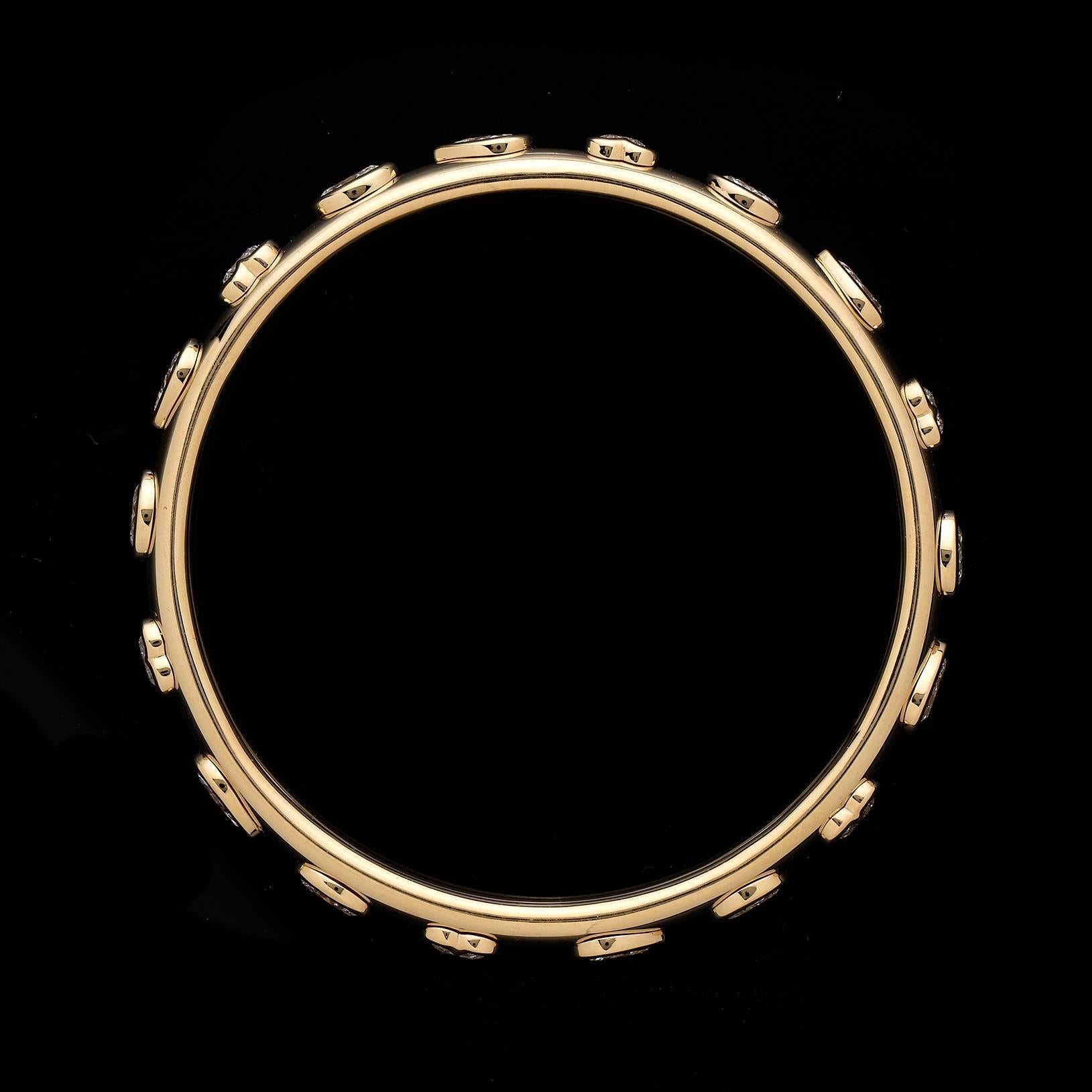 The 18k yellow gold bangle bracelet is decorated all the way around with 18 bezel-set assorted fancy shaped diamonds, including heart, pear, and oval-shaped, and round brilliant-cut diamonds, all together weighing a total of 9.58 carats. The bangle