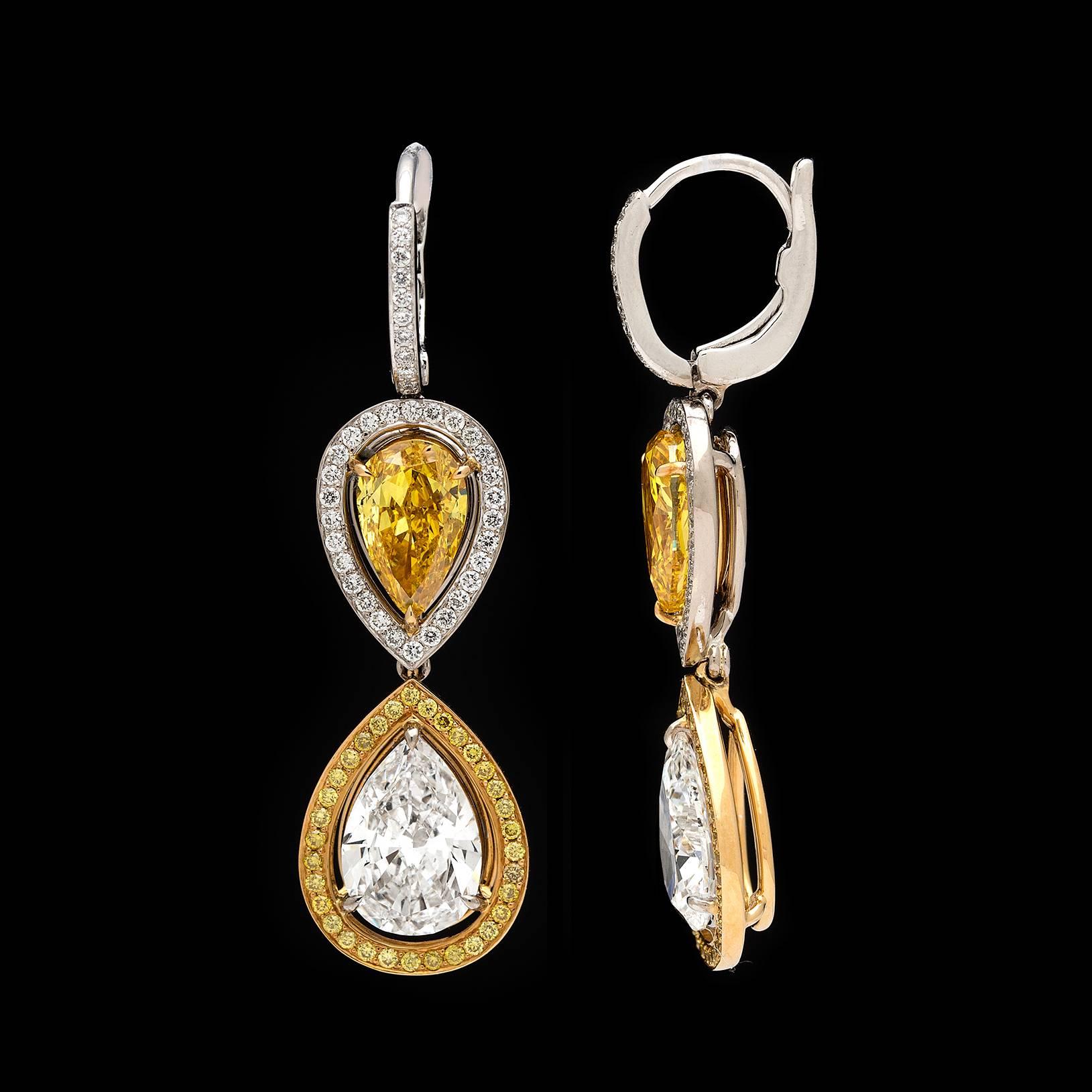 One-of-a-kind incredible 1 white and yellow gold drop earrings each featuring a GIA 1.01-carat Fancy Vivid Yellow and 1.11-carat Fancy Vivid Orangy Yellow pear-shaped diamond, surrounded with near colorless round brilliant-cut diamonds, suspend a