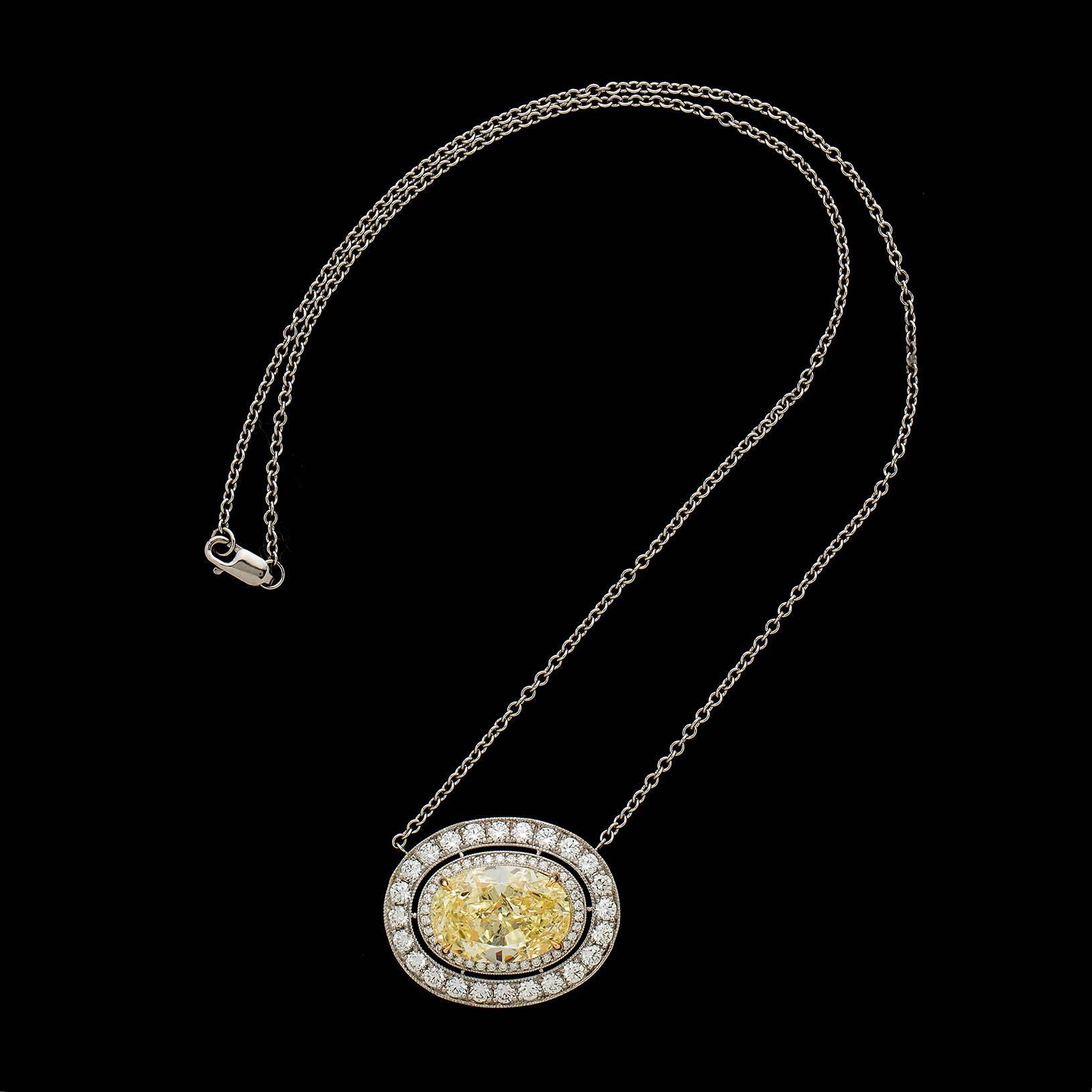 A truly extraordinary platinum and 18k yellow gold pendant-necklace featuring a fancy yellow oval-shaped diamond weighing 8.49 carats, surrounded by two concentric halos of near colorless round brilliant-cut diamonds, weighing in total 1.87 carats.
