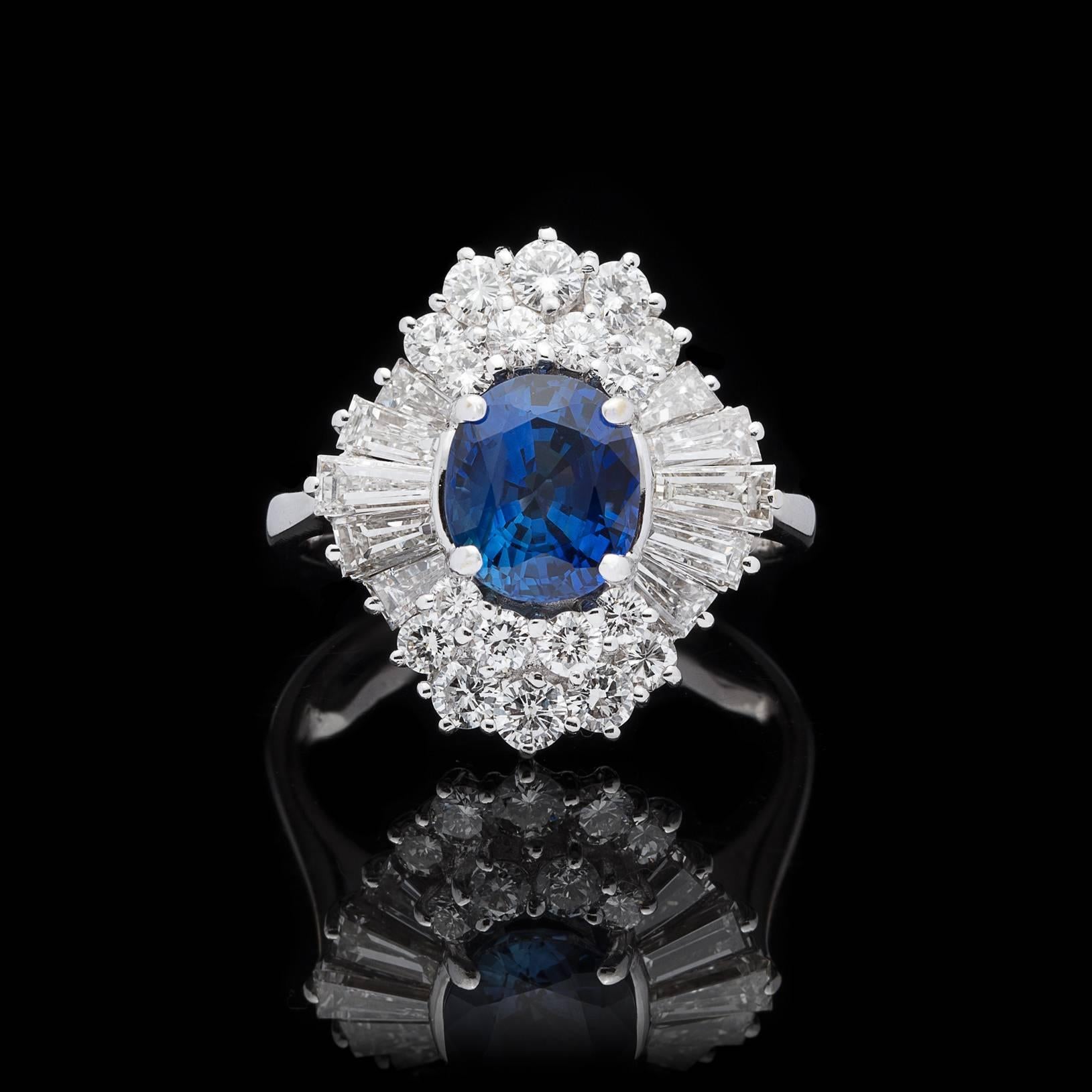 A timeless design featuring an exceptionally vibrant Oval Cut Blue Sapphire weighing approximately 2 carats, surrounded by approximately 1.76 carats of fine Round and Tapered Baguette Cut Diamonds. This white gold stunner weighs 7.2 grams, is