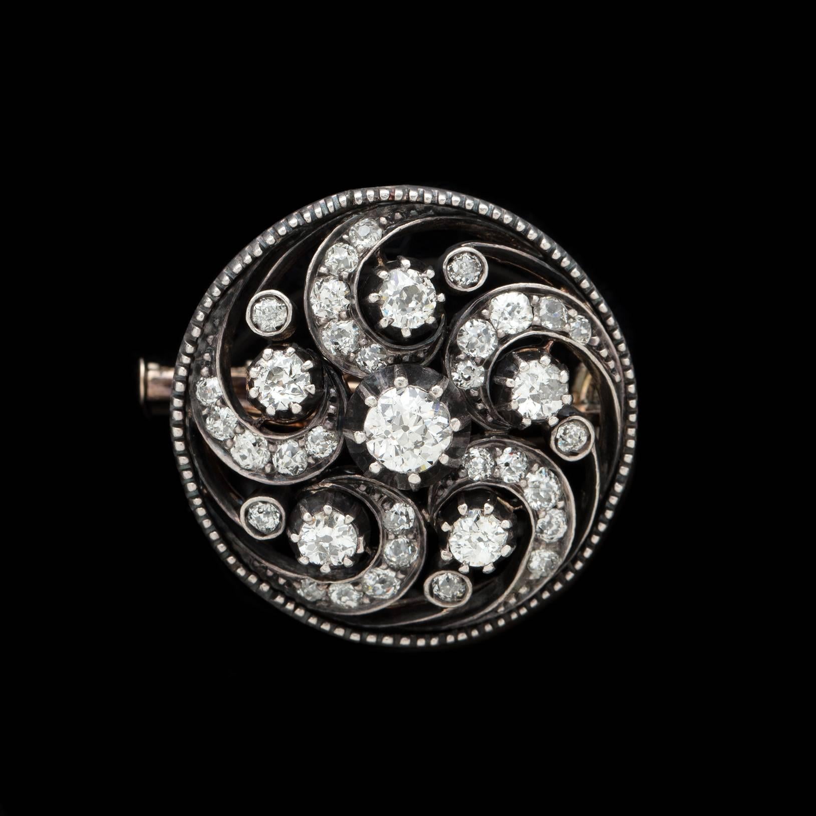 Beautifully crafted swirl motif Diamond Pin featuring approximately 2.25 carats of impressive round diamonds. 36 diamonds are expertly set in a combination of 14 karat yellow gold and silver construction, as was common for the period. The piece