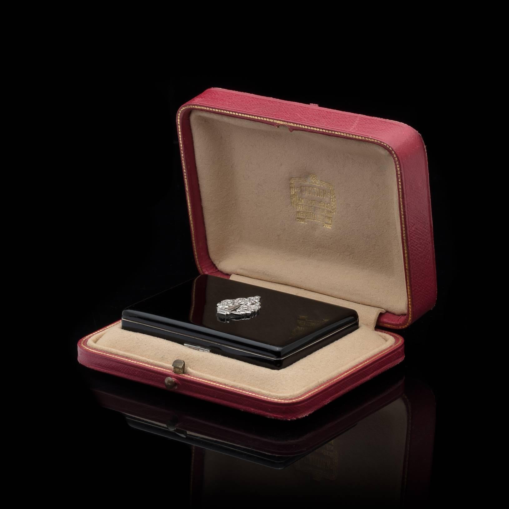 An exceptional piece of beauty. The Cartier rectangular gilt silver and black lacquer compact, with interior beveled mirror, lipstick and powder well, features lid with diamond-set platinum potted tree appliqué, and the platinum thumb push with