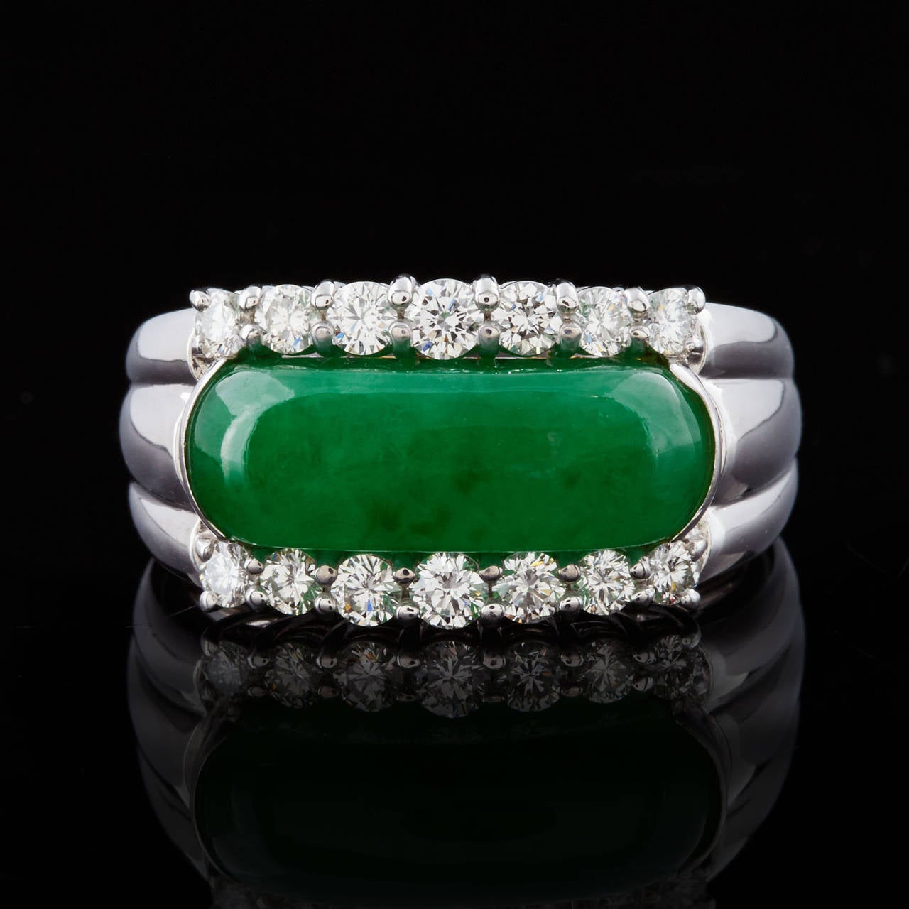 18Kt White Gold Ring Features an Oval Arc Shape Cabochon GIA Graded Translucent Green Jadeite Jade with Natural Color and No Indications of Impregnation. Along the top and bottom of the stone are a total of 14 fine diamonds with 0.56 approximate