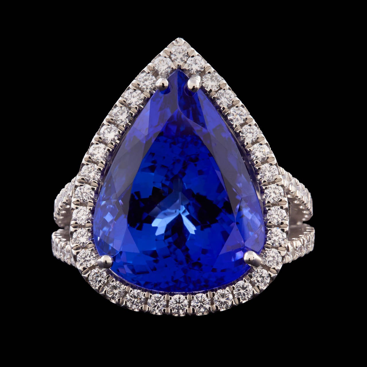 Platinum Cocktail Ring Features a Stunning Natural Vivid Blue 12.67 Carat Pear Shape Tanzanite set in a Halo of Round Brilliant Cut Diamonds. Additional diamonds are accented down the shank and along the gallery. There are 132 round brilliant cut