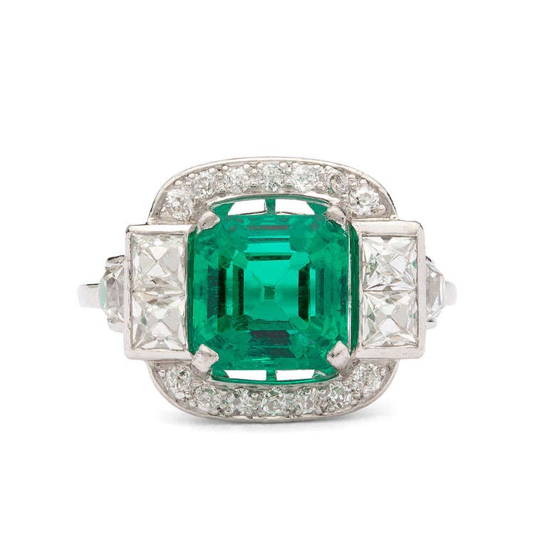 Platinum Art Deco Ring with stunning 2.74ct Asscher Cut Colombian Emerald Adorned with 6 French Cut Diamonds for approximately 0.72ct and 14 Round Cut Diamonds for 0.20ct, totaling 0.92ct diamond weight. The ring is a size 7 and weighs 4.9 grams.