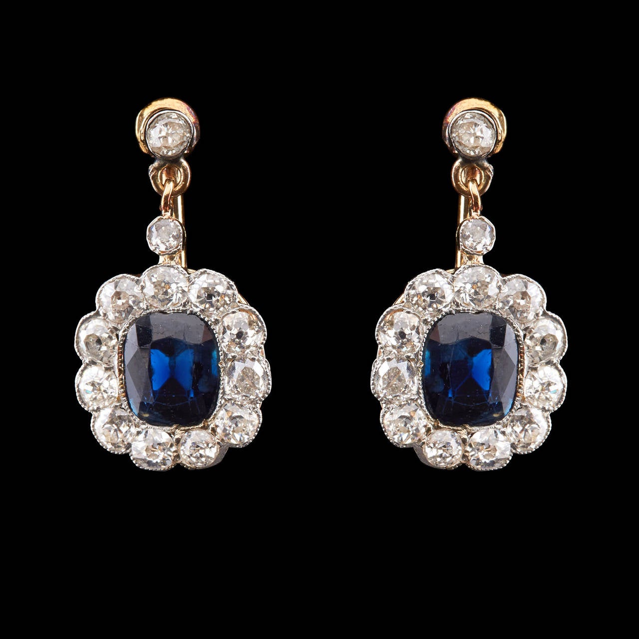 14Kt Yellow Gold Dangle Screwback Earrings features Cushion Cut Blue Sapphires totaling 2.50 carats surrounded by 13 Old Mine Cut Diamonds totaling 1.84 carats. The total length is 0.88″ and 0.50″ wide. Total item weight is 4.9 grams.