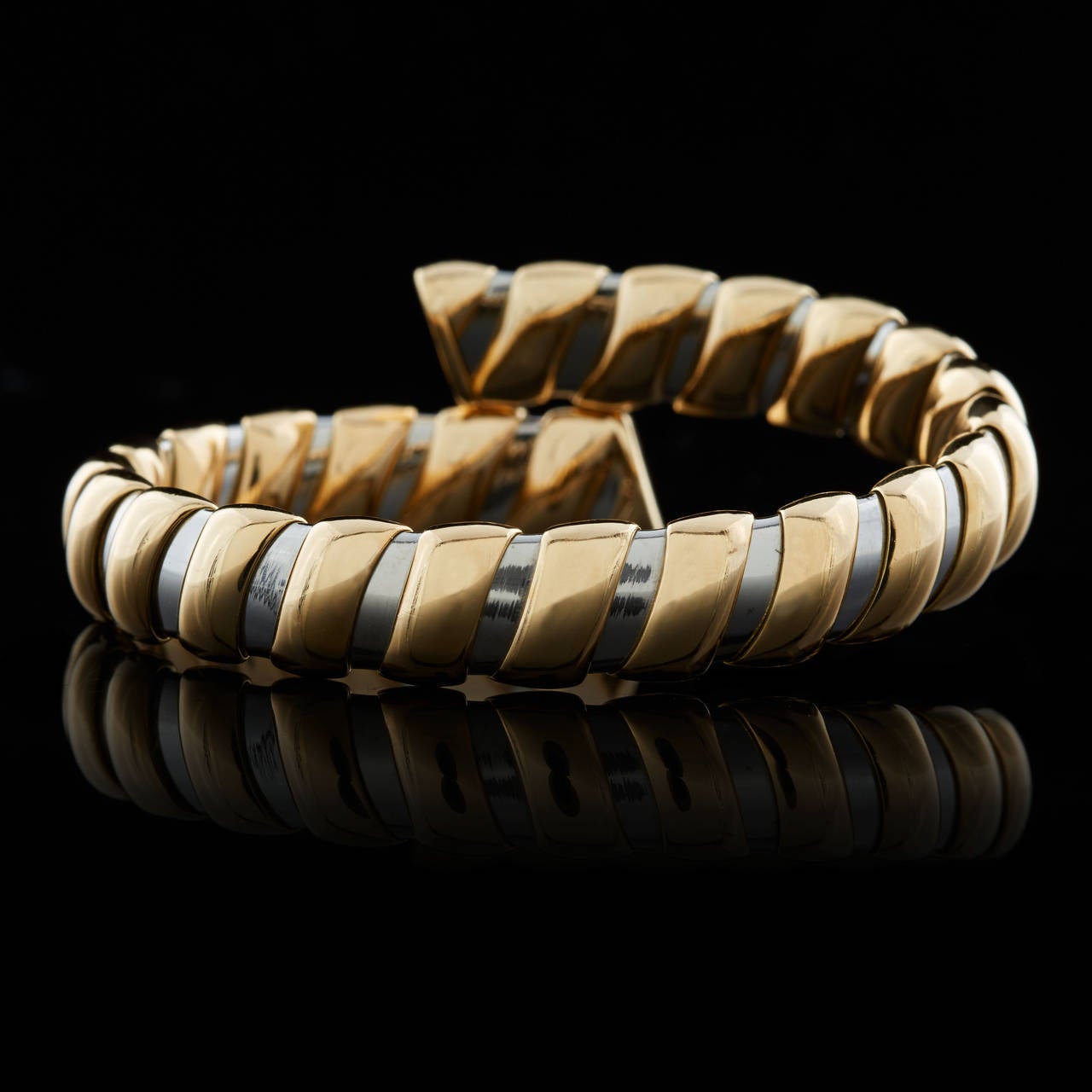 Bulgari 18Kt Two-Tone Yellow and White Gold Twist Design Bangle Bracelet with a Flexible Feel. The bracelet measures 8 inches around and 10mm wide, with a weight of 43.6 grams.