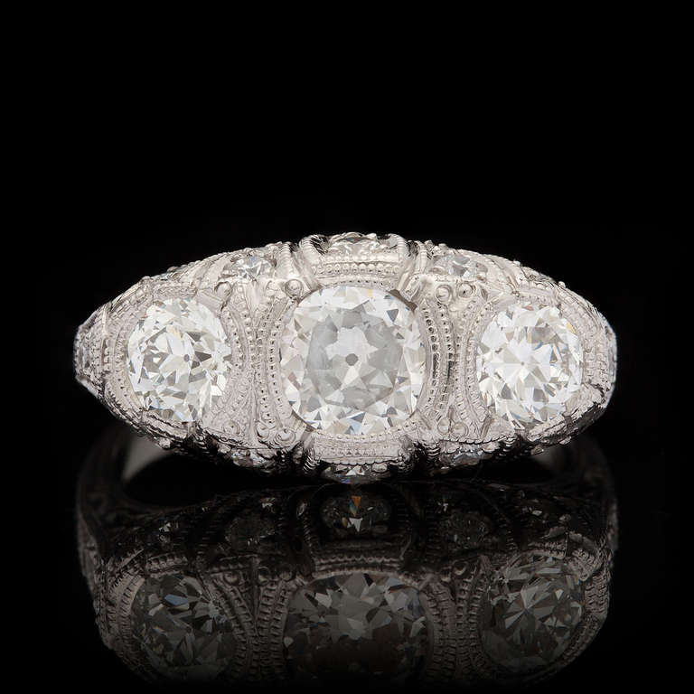 This Custom made Platinum Traditional Style Ring Features a 0.63ct Old Mine Cut Diamond with I-J color and SI clarity.  The main stone is accented by two round diamonds and an additional 22 smaller round diamonds totaling another 1.38cts.   The ring