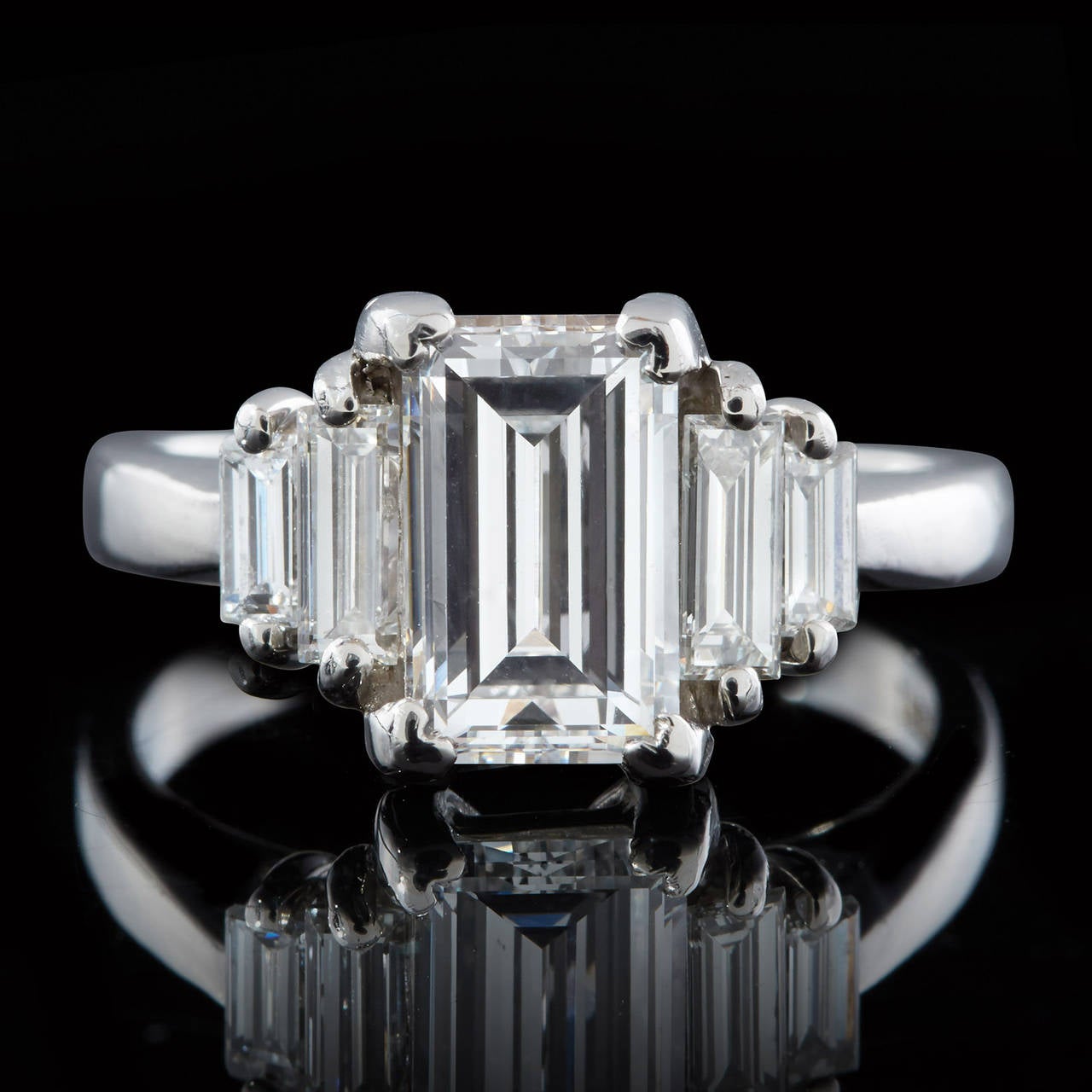 Platinum Emerald Cut Diamond Ring features a center GIA certified 2.02 carat E VS2 Diamond accented with Emerald Cut Side Diamonds totaling 0.54 carats giving a total diamond weight of 2.56 carats. The width of the ring band is 2.7mm and weighs 8.6
