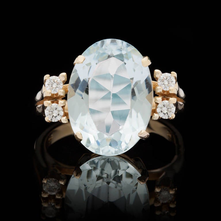 18KT Yellow Gold Ring Features an Oval Shape Aquamarine for approximately 6.0cts, flanked by 4 round diamonds for a total approximate weight of 0.20cts. The ring is a size 6.75 and weighs 7.0 grams.