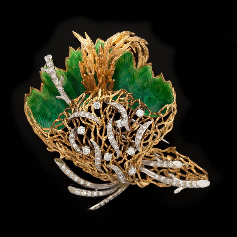 Beautiful 18Kt Yellow and White Gold, circa 1970s, Italian Brooch Features 66 Diamonds Enhancing an Abstract Nest of Branches and Green Enamel Leaves. The round brilliant and single cut diamonds total approximately 1.45cts. The brooch measures 3.0