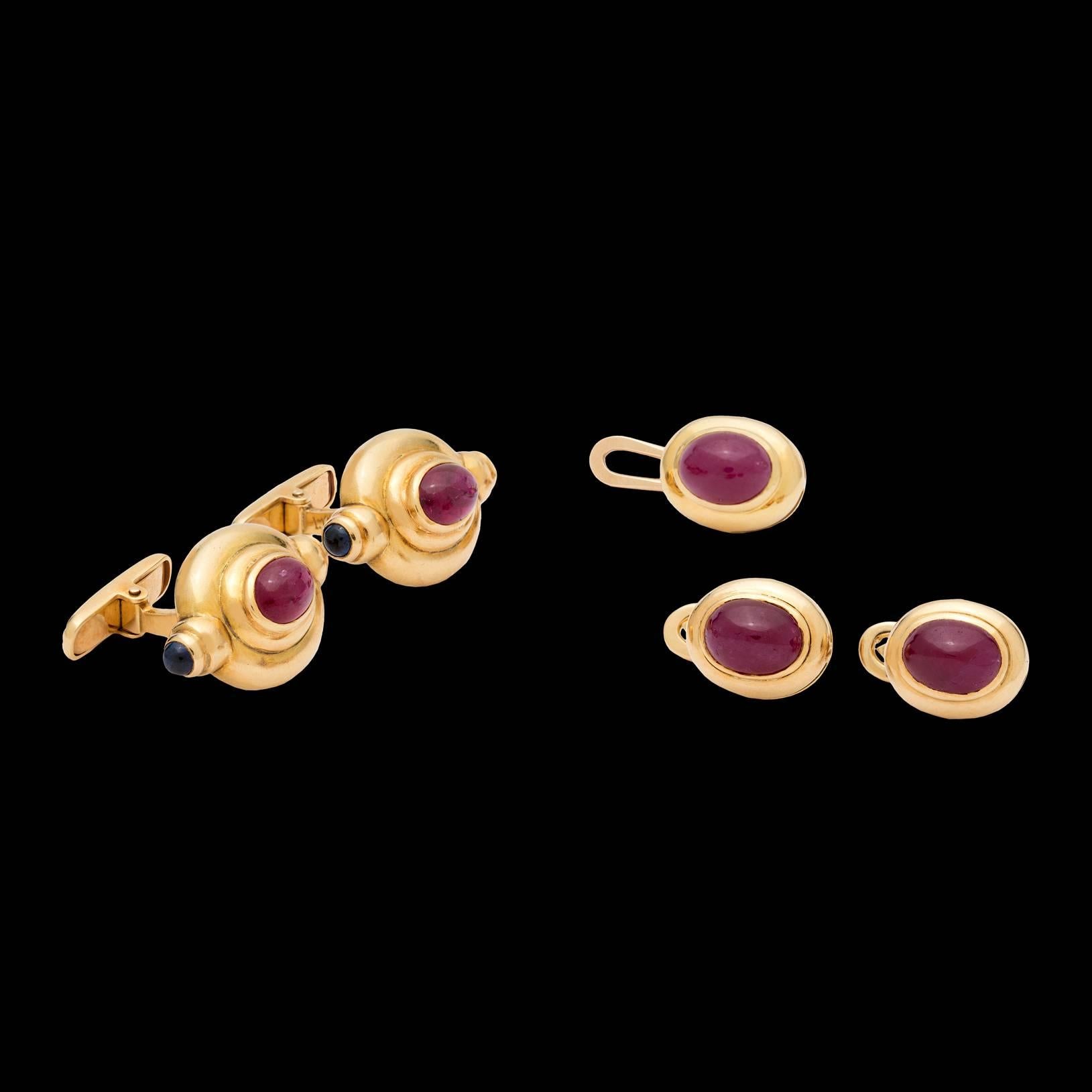 18k yellow gold set of swivel cuff links and 3 shirt studs designed with cabochon rubies and sapphires. The face of the cuff link measures 1″ x 0.62″, and the shirt stud measures 0.50″ x 0.43″. Total weight of the 5 piece set is 26.5 grams.