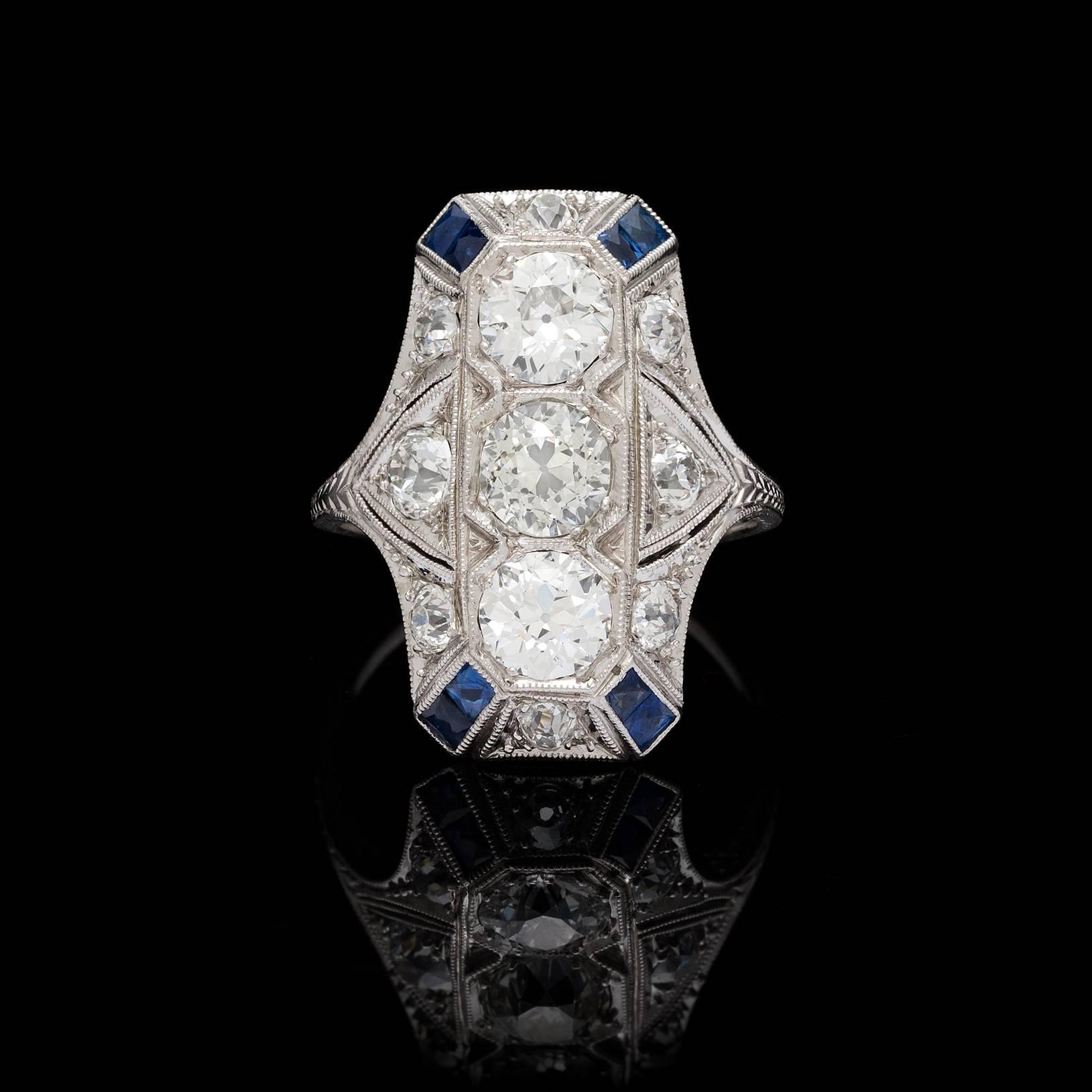 Art Deco platinum 2.00 carat total weight diamond detailed with blue sapphires. Three old European cuts vertically set total 1.60 carat weight, the center warmer in color than the surrounding stones. This gorgeous piece features engraving and