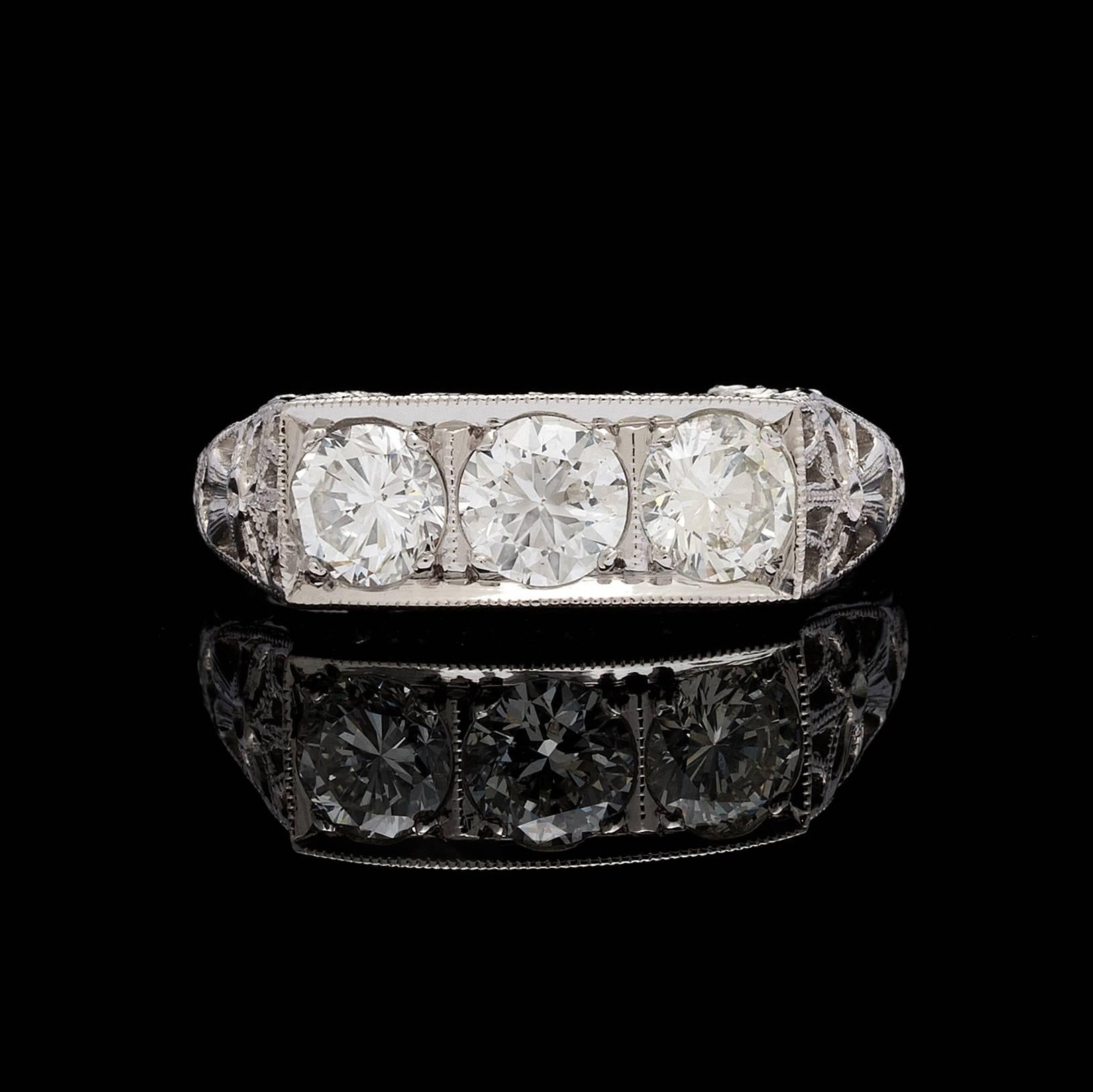 3 round brilliant cut diamonds totaling 1.38 carats set in a filigree design platinum ring detailed with milgrain, openwork, and engraving work. Ring size is a 6.25 and can be resized. Total weight of the ring is 7.8 grams. 