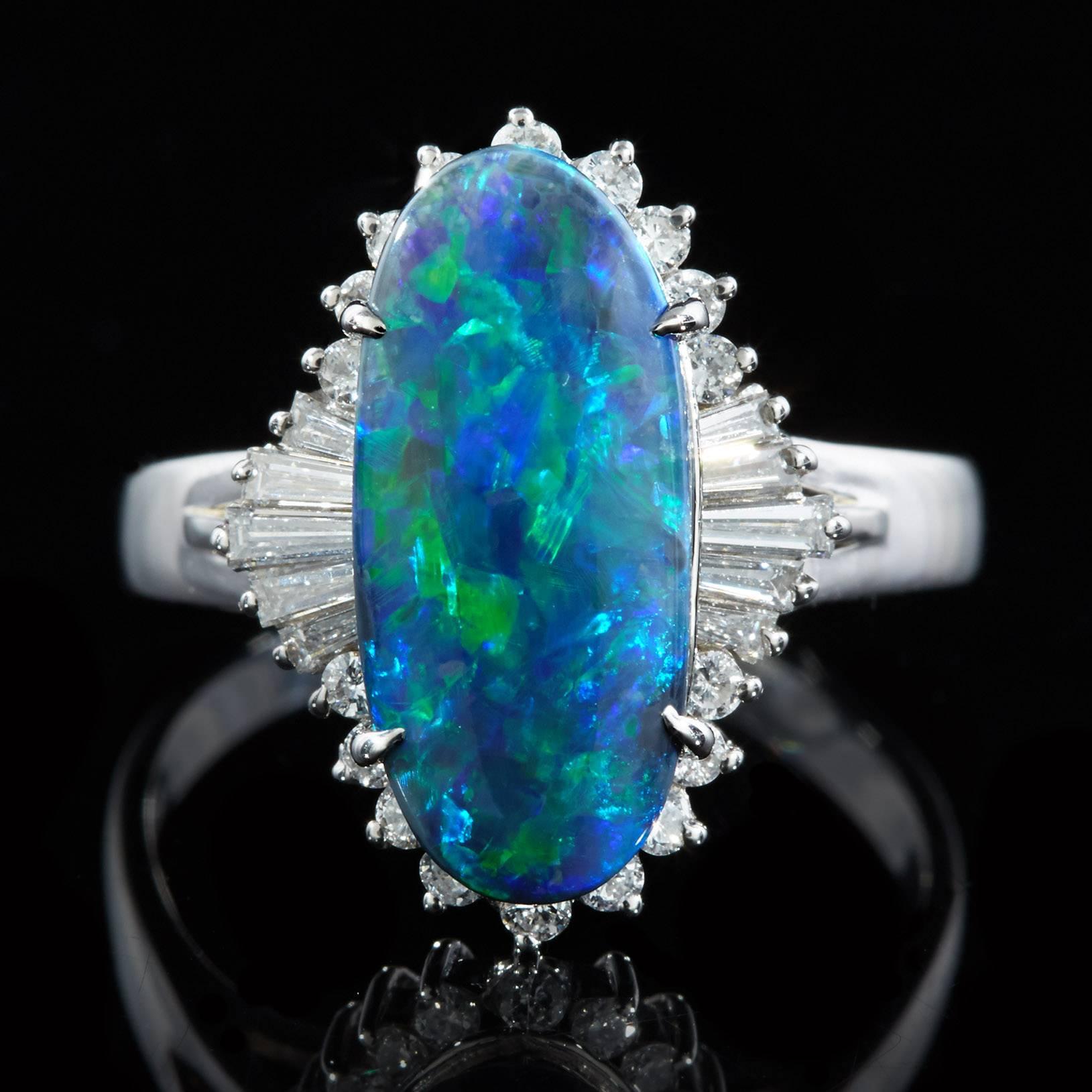 Fabulous Platinum Ring features a Cabochon Cut Black Opal displaying Blue and Green Play of Color. This opal measures 15.71 x 7.0 mm. A total of 28 round brilliant cut and tapered baguette cut diamonds surrounds the opal with a total of 0.47 carats.