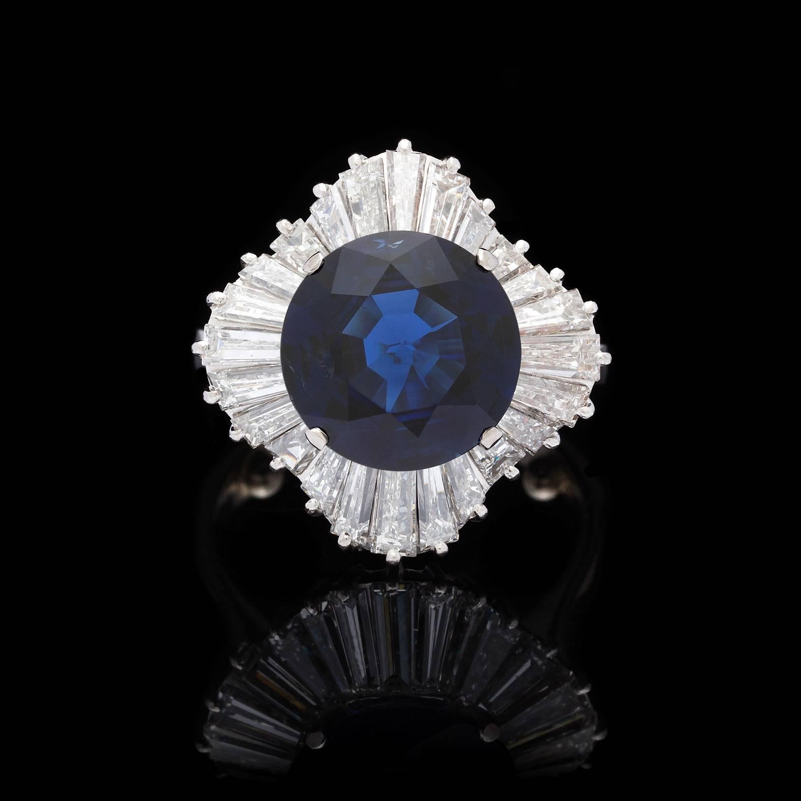 Fantastic vintage 18k white gold ballerina ring featuring a GIA graded round cut 5.39 carat deep blue sapphire in a halo of artfully set tapered baguettes. The 25 diamonds of substantial size total 3.00 carat total weight. The ring is approximately