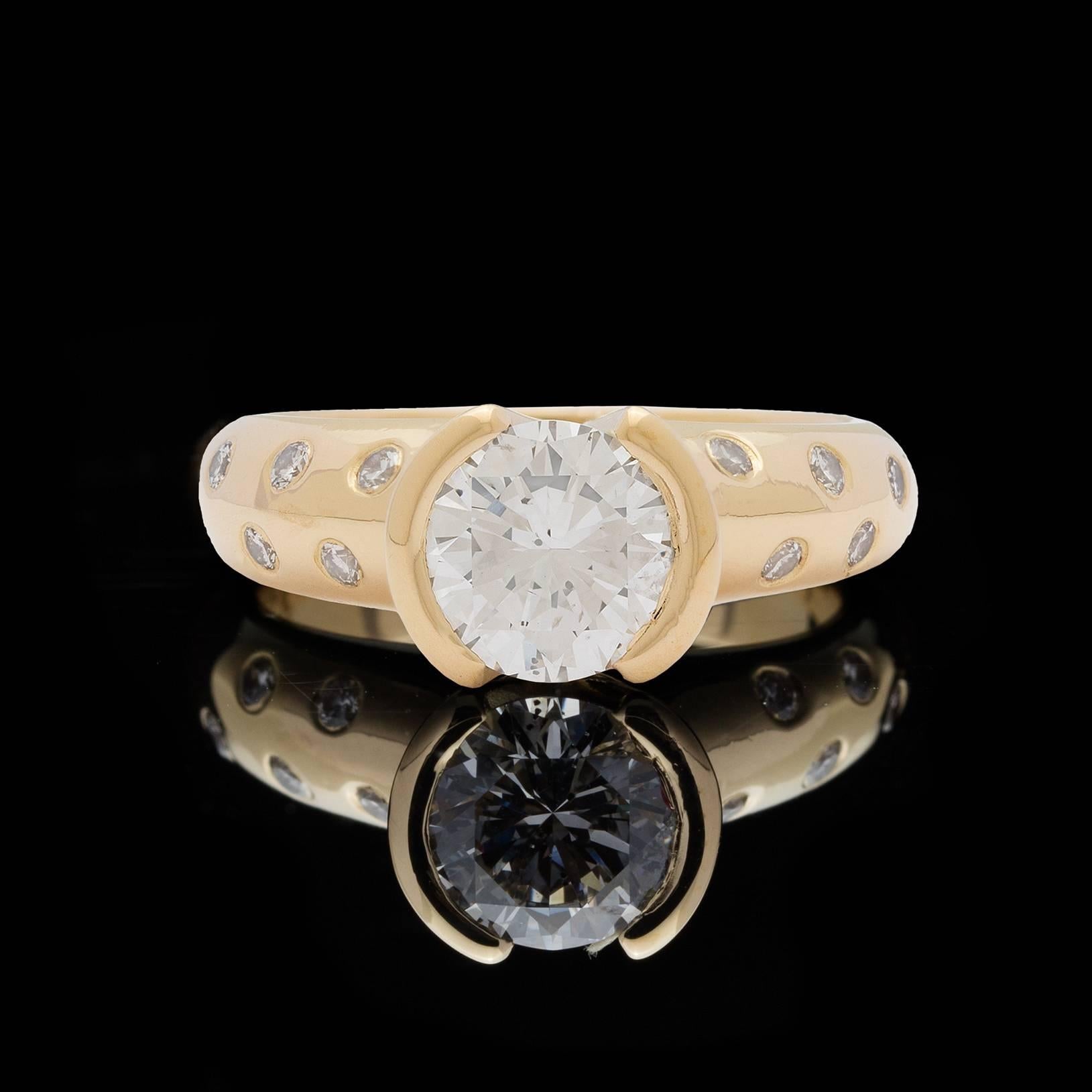 18k yellow gold etoile band ring features a 1.20 carat round brilliant cut diamond set in a half bezel mounting. Flushed-set on the sides are 10 round brilliant diamonds totaling 0.10 carats. Ring size is a 4.75 and can be sized. Contemporary look