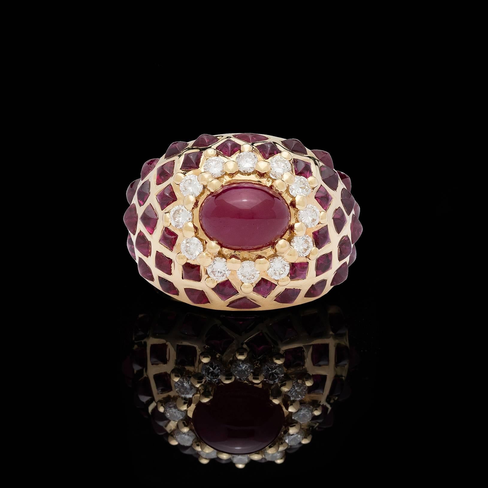 Decadent vintage ruby and diamond ring featuring an oval cabochon ruby measuring approximately 9.25mm by 7.5mm prong set within a halo of 12 round brilliant cut diamonds totaling approximately 0.60 carat. The additional rubies set in a lattice