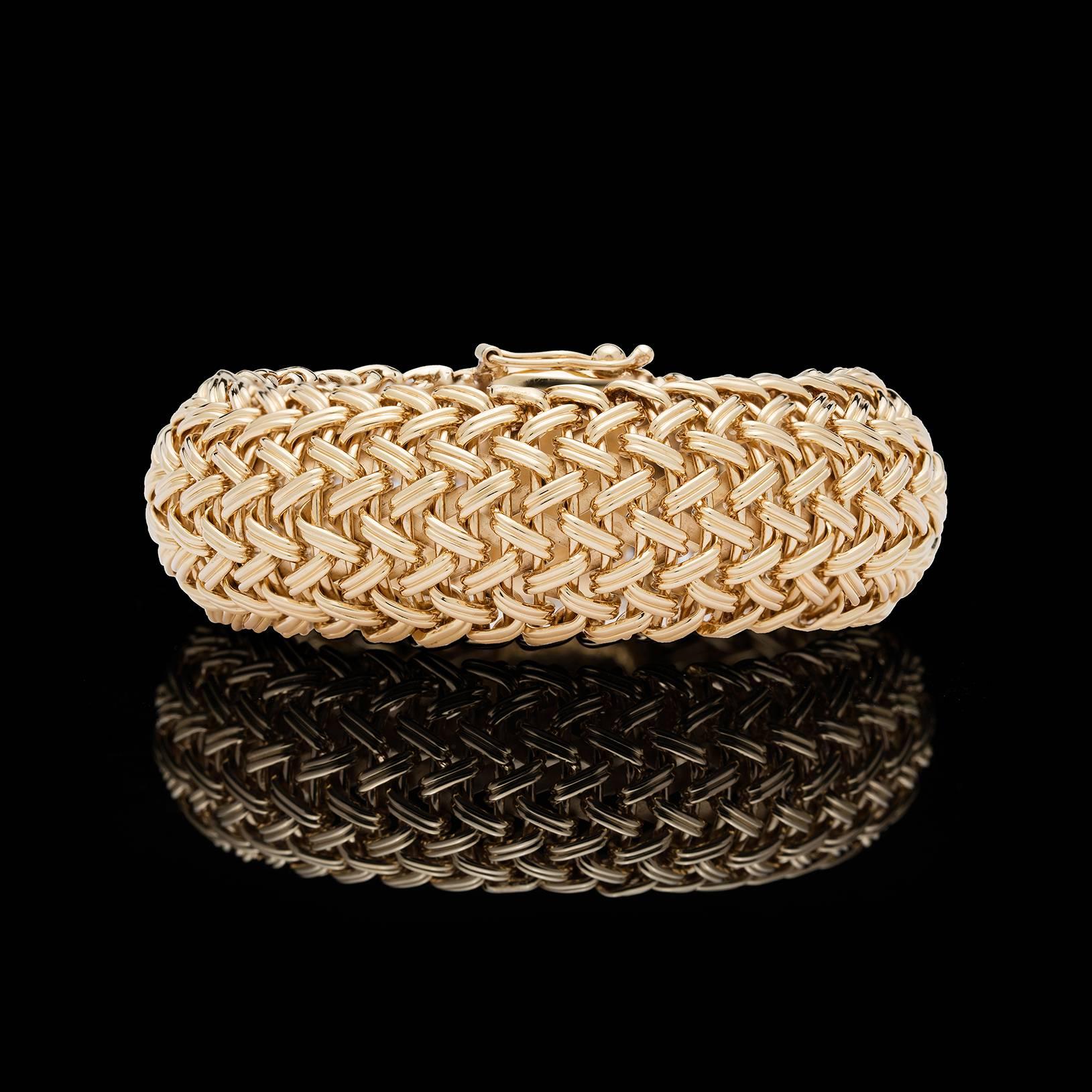 Eye-catching 14k yellow gold woven style wide bangle bracelet. Length is 7 inches, and width is about 1 inch. Total weight of the bracelet is 87 grams. This substantial piece will be a wardrobe favorite!  