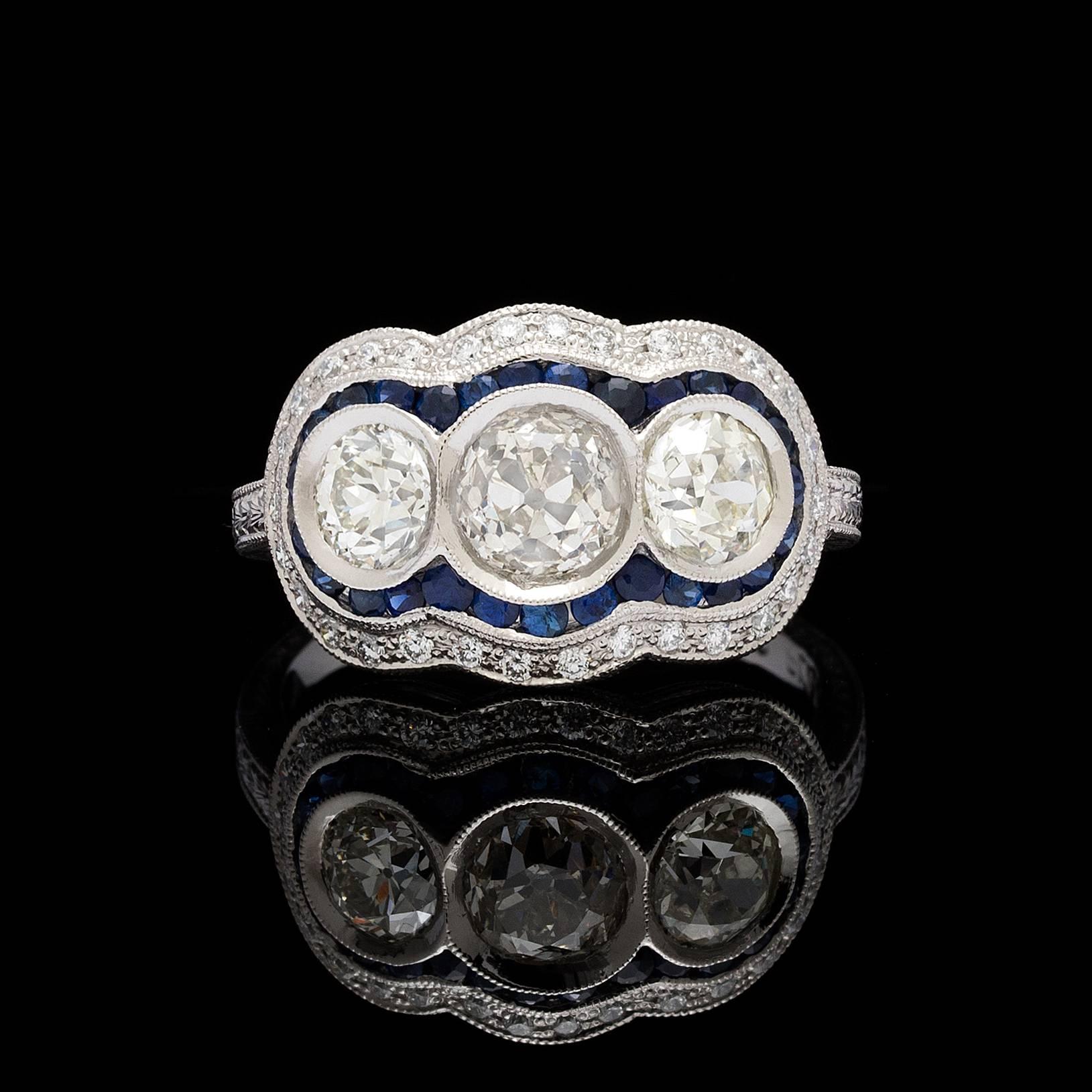 Platinum Art Deco style ring features 3 old european cut diamonds, the center is 0.86 carats and 2 sides are 0.97 carats for a total of 1.83 carats. The ring is detailed with 0.20 carats of round brilliant cut diamonds and 0.54 carats of blue