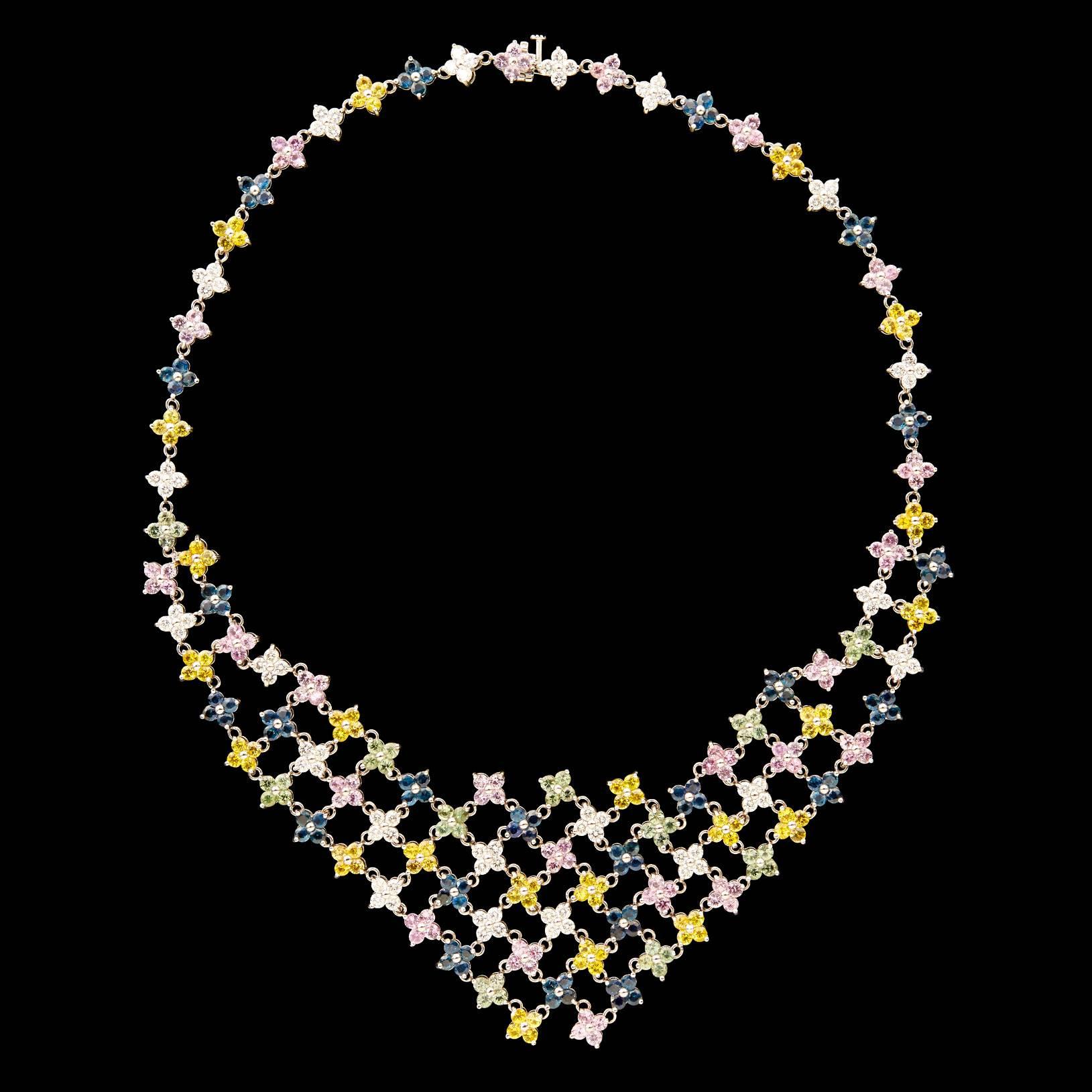 Outstanding Floral Bib Necklace of Sapphires and Diamonds Set in 18Kt White Gold. The colorful gemstone flowers comprised of 9.10 carat total weight  diamonds, 12.32 carat total weight blue sapphires, 12.32 carat total weight yellow sapphires, 12.88