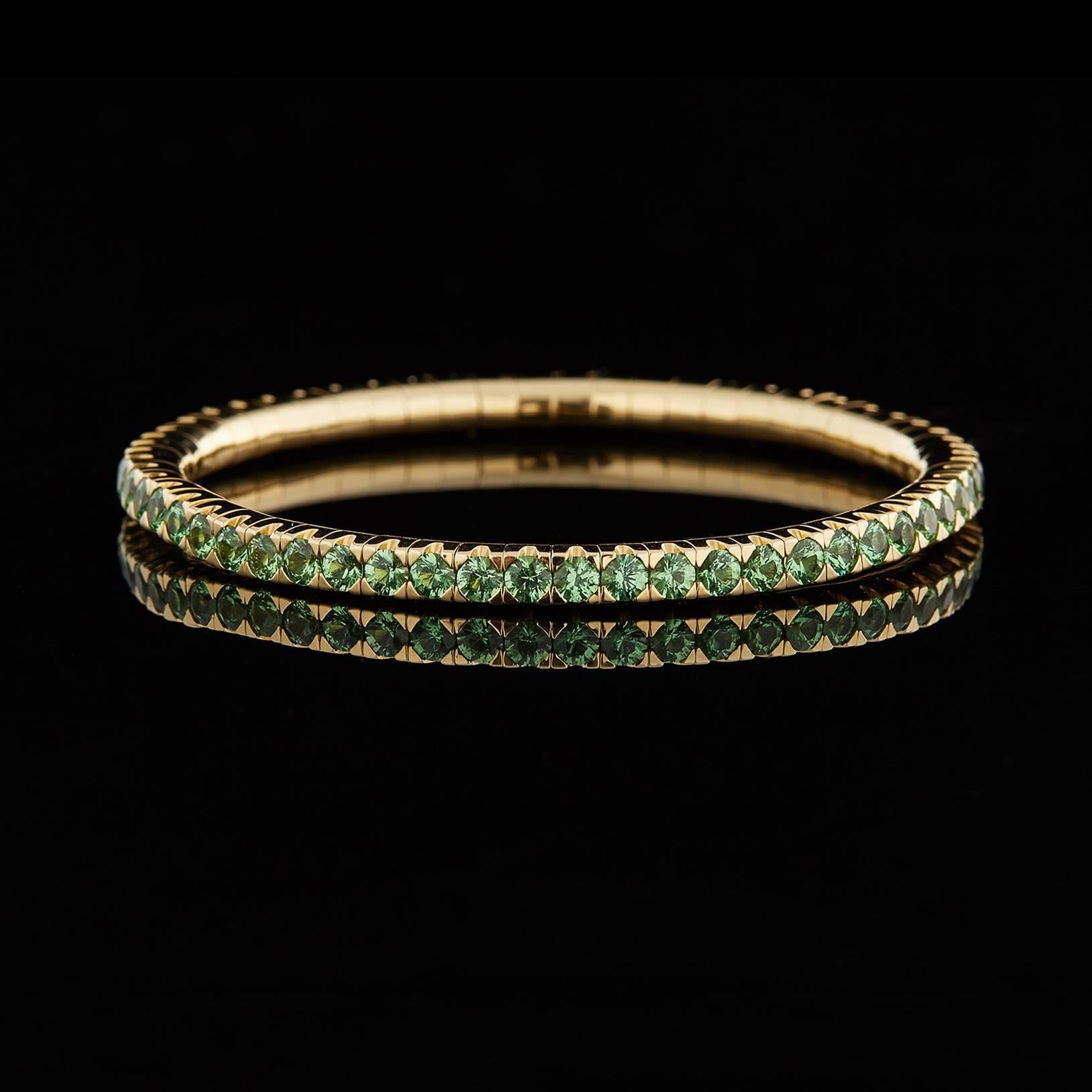 Mattia Cielo's beautifully crafted 18k yellow gold flexible 'Universo Tennis Bracelet' features prong-set round brilliant-cut tsavorites on an expandable, metal-spring narrow bangle design. Estimated total tsavorite weight is 6.12 carats.The