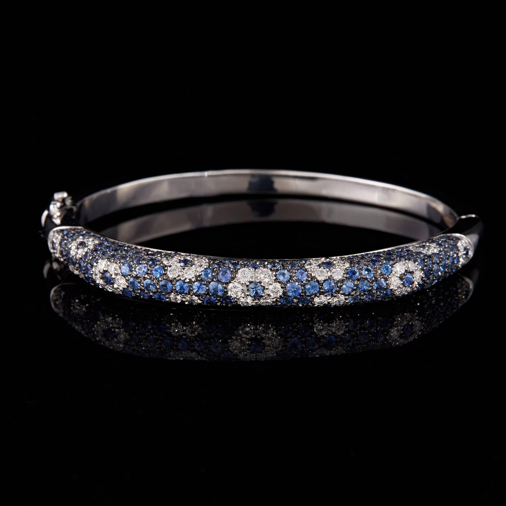 The Italian designer Salavetti 18k white gold bangle bracelet featuring pavé-set round brilliant-cut diamonds and blue sapphires, in a contemporary floral motif. The diamonds weigh a total of 1.63 carats and the sapphires weigh 3.04 carats total.