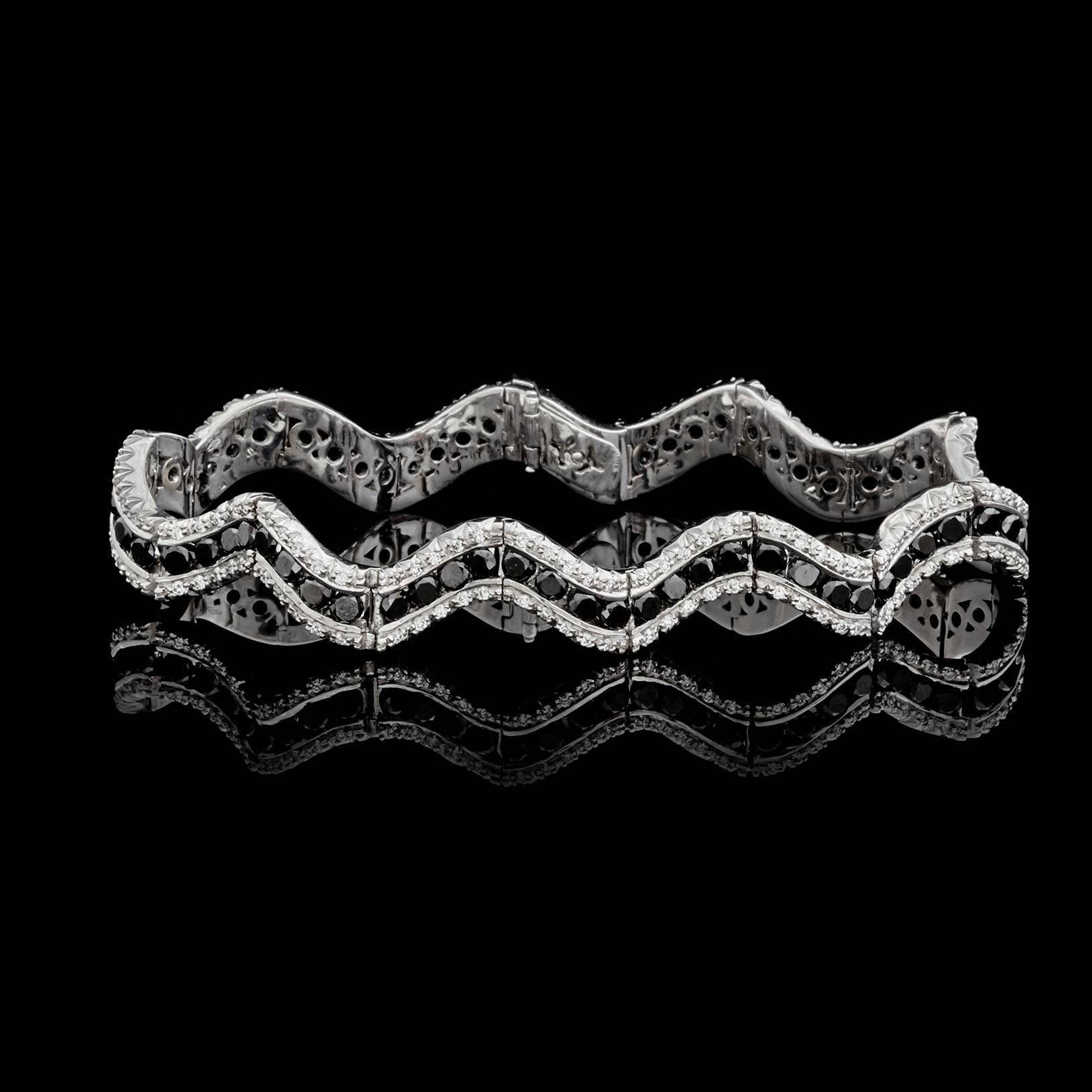 Favero 18k white gold wave design bracelet features 6.72 carats of round brilliant-cut black diamonds, bordered by round brilliant-cut white diamonds weighing in total an estimated 1.21 carats. The stylish design bracelet measures 7 inches in