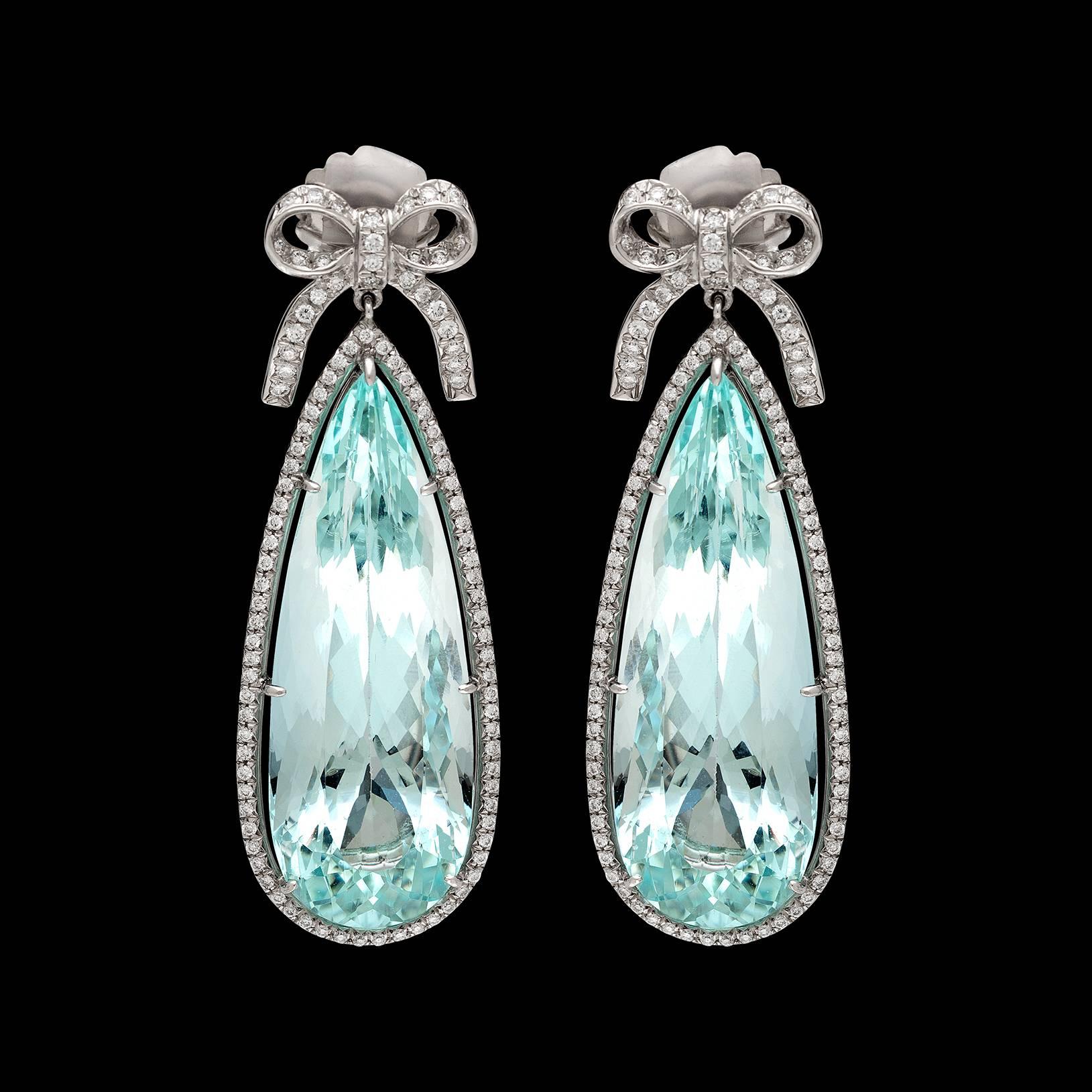 These vibrant platinum earrings are designed with two fine pear-shaped aquamarines, weighing 34.37 and 33.52 carats, surmounted by bow motif tops, framed with 208 round brilliant-cut diamonds, weighing in total an estimated 1.29 carats. The drop