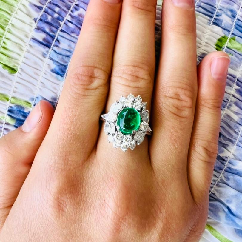 Auffällige Farbe und Klarheit! Der Platinring zeigt einen intensiv grünen Smaragd-Cabochon mit einem Gewicht von 1,69 Karat, umgeben von Diamanten im Marquise-, runden Brillant- und Baguetteschliff, Farbe F-G und Reinheit VS, mit einem Gesamtgewicht