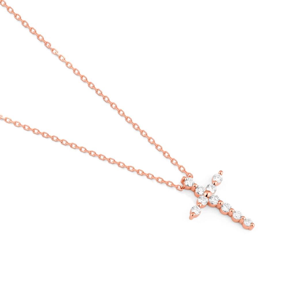 Este delicado colgante en forma de cruz está elaborado en oro rosa de 18 ct y adornado con diamantes talla brillante que le confieren un brillo suave y elegante. La calidez del oro rosa realza la silueta atemporal, creando una pieza a la vez