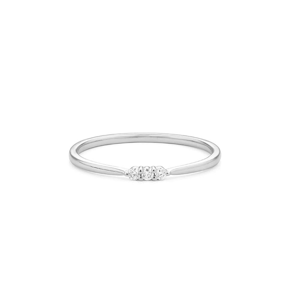 Semplice e raffinato, questo anello è realizzato in oro bianco 18 ct e presenta tre diamanti taglio brillante incastonati su una sottile fascia lucida. Le sue linee pulite e il suo profilo minimale lo rendono perfetto per essere impilato, regalato o