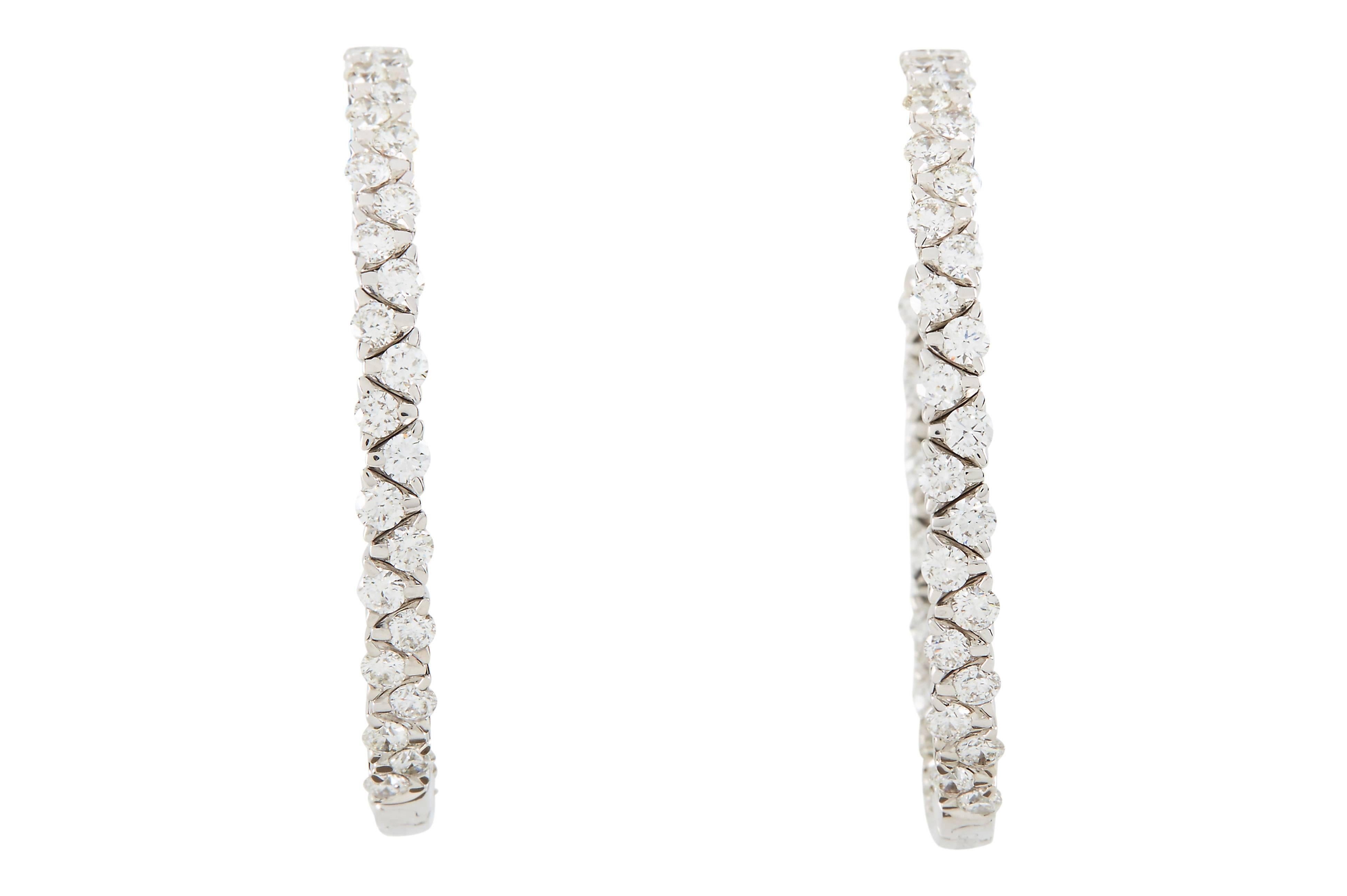 A pair of 18k white gold inside-out diamond hoop earrings set with 8.02 carats, total weight, of round brilliant-cut G/VS  diamonds.
The posts are angled to prevent hoops from turning outward, with large friction earring backs. 
The outside