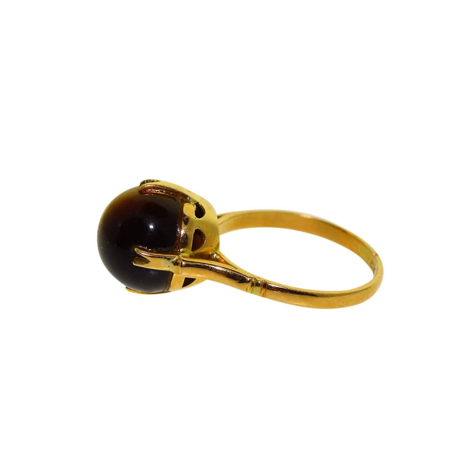 This charming little ring is set with a 10 millimeter Tiger Eye Stone. 
The ring is a size 5.
Stamped with an 18Kt. Hallmark it appears to be of English origin and entirely hand constructed.
This is a nice ring for a young lady. 
