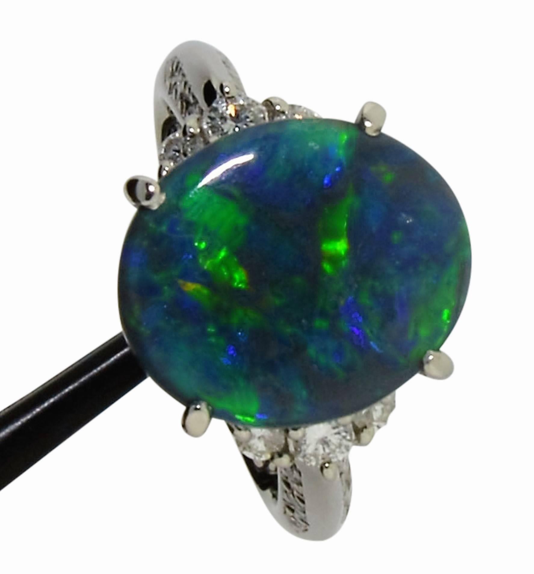 This classic ring features a natural black opal  weighing 3.42cts, displaying flashes of vivid, bright blues and greens. Hand constructed in platinum, it contains 18 bright white round diamonds, all SI/VS clarity, E/F Color, totaling 0.27cts, sit on