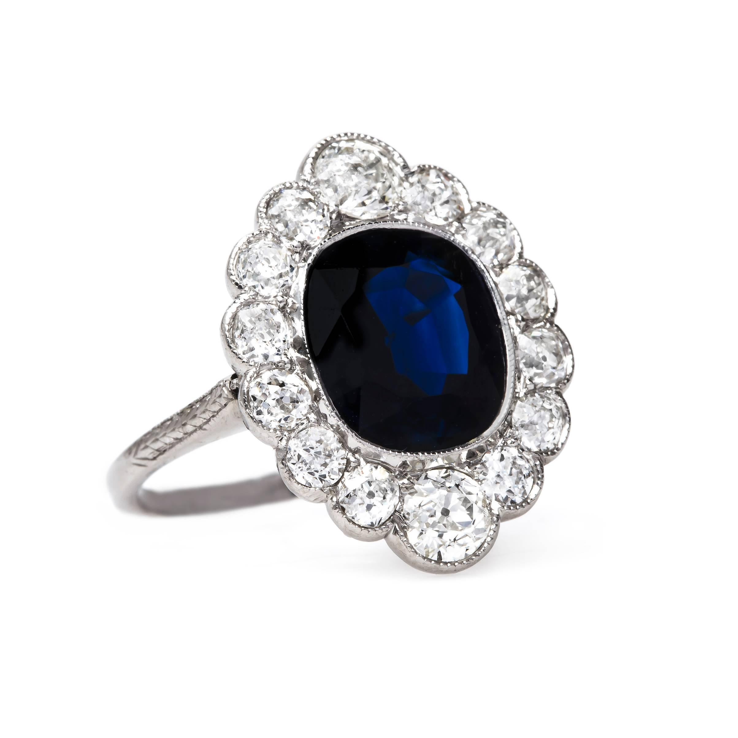 Long Grove is an exceptional and authentic Edwardian (circa 1915) platinum engagement ring. This incredibly romantic ring centers a Cushion Cut natural sapphire gauged at approximately 4.10cts accompanied by a Guild Laboratories certificate stating
