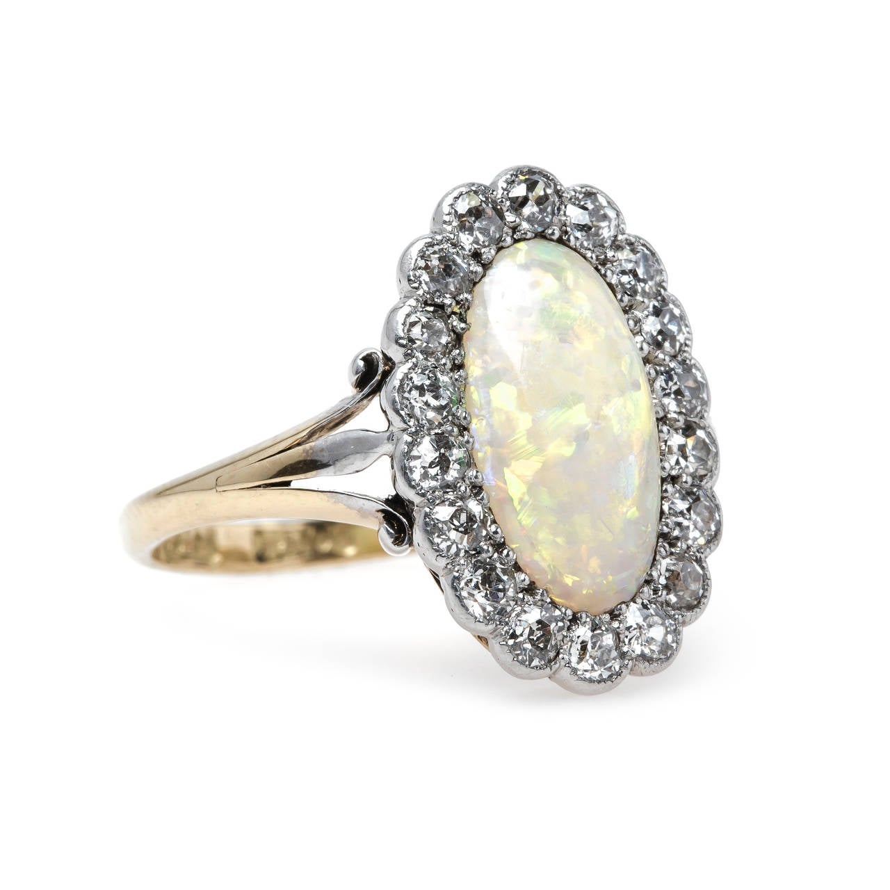 Argyle is a captivating authentic Victorian era (circa 1890) platinum topped 18k yellow gold ring centering an elongated oval cabochon opal gauged at 11.9mm x 6.4mm that glows warmly with a beautiful predominantly green and orange play-of-color.