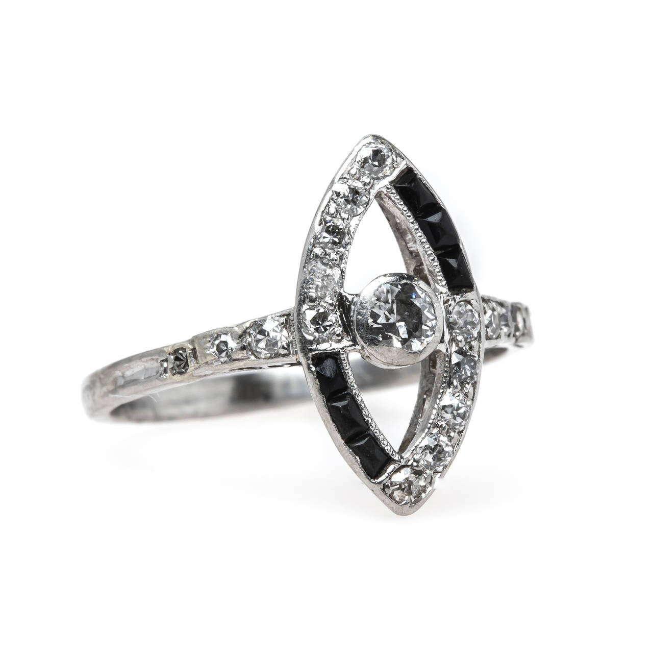 Emeryville is a remarkably unusual Art Deco (circa 1925) platinum navette shaped ring centering a bezel set Old European Cut diamond gauged at 0.12ct and framed by a marquise shaped halo of sixteen Old Full Cut diamonds totaling approximately 0.28ct