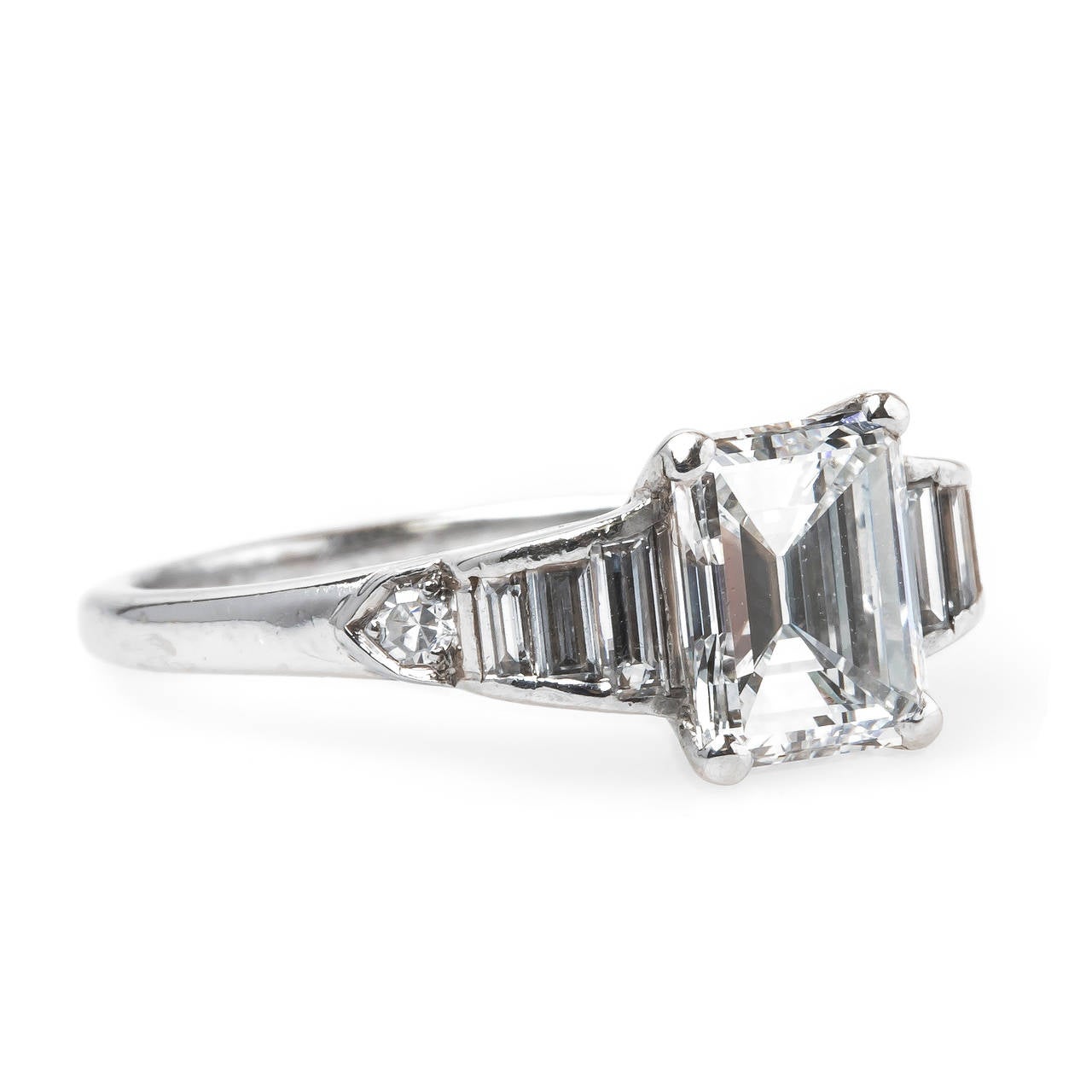 Silverlake is an incredible authentic Late Art Deco platinum ring that epitomizes design from the 1930's. The ring centers a four-prong set 1.35ct EGL certified Emerald Cut diamond graded F color and VS1 clarity. This high quality center diamond is