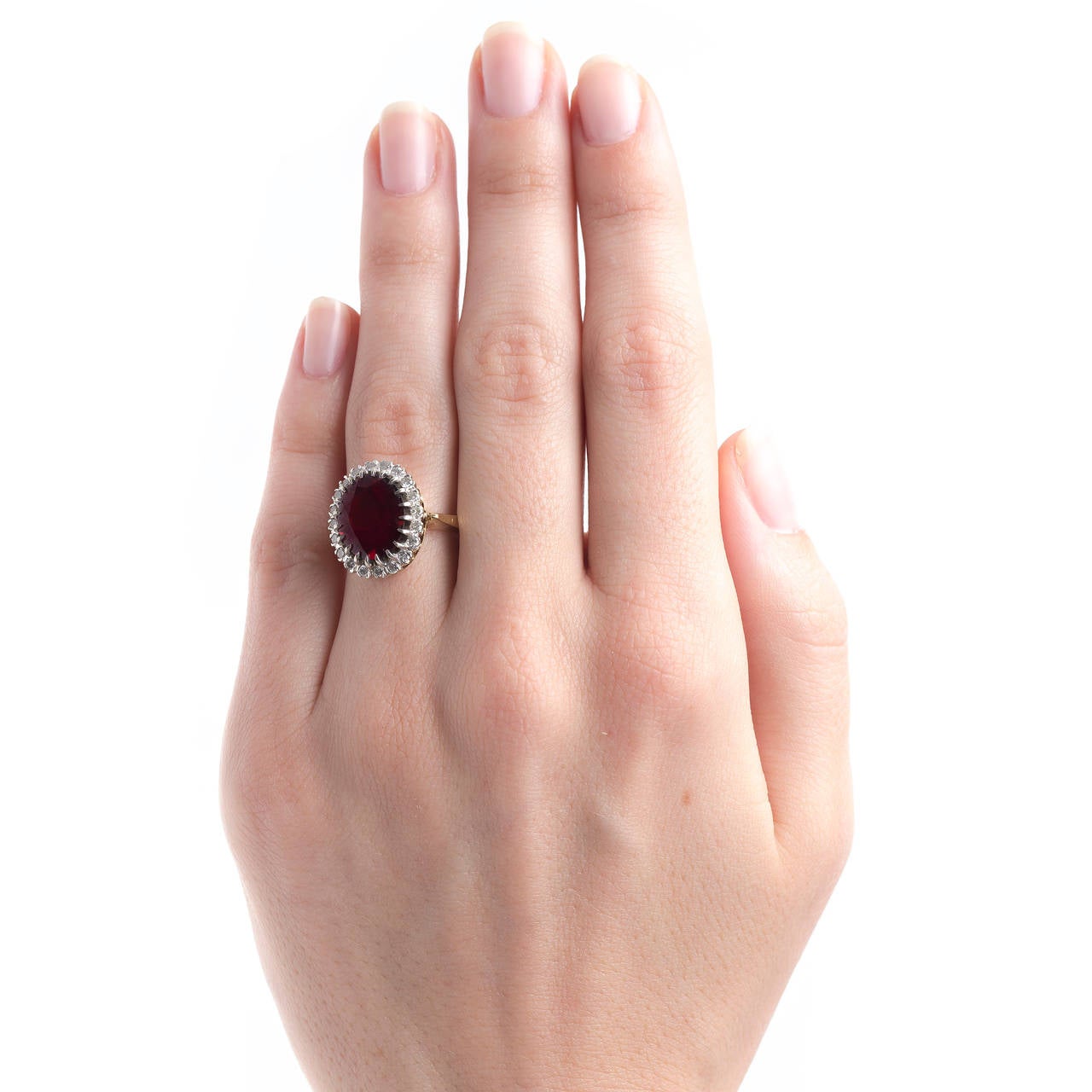 Peppertree Lane is a fantastic authentic Retro era (circa 1945) 14k yellow and white gold ring centering an oval slightly brownish-red Oval garnet gauged at 5.50ct surrounded by a beautiful halo of twenty Round Brilliant Cut diamonds totaling