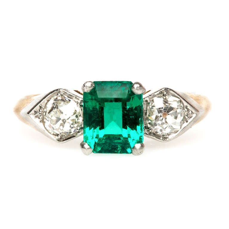 Garden Park is a gorgeous Edwardian Era emerald ring made from platinum topped 14k yellow gold. Garden Park features a 1.46ct GIA certified Step Cut Columbian emerald, nestled between two Old Mine Cut diamonds set in a shield shape setting totalling