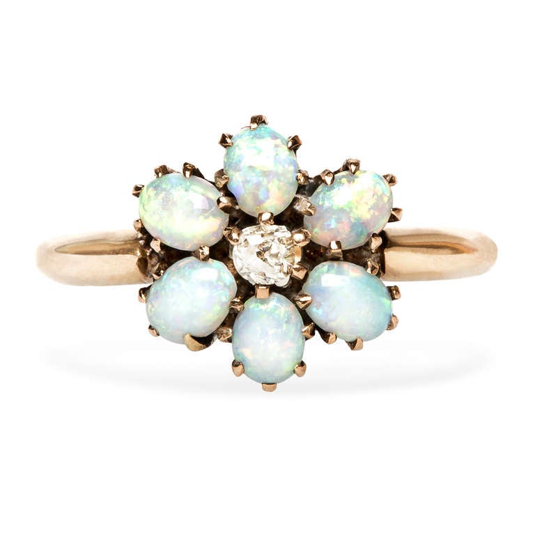 Highland Park is a playful Victorian Era opal cluster ring, made from 14k yellow gold. Highland Park features a 0.07ct Old Mine Cut diamond, surrounded by six pretty oval opals with a fiery orange, green and blue play of color.  This fun ring also