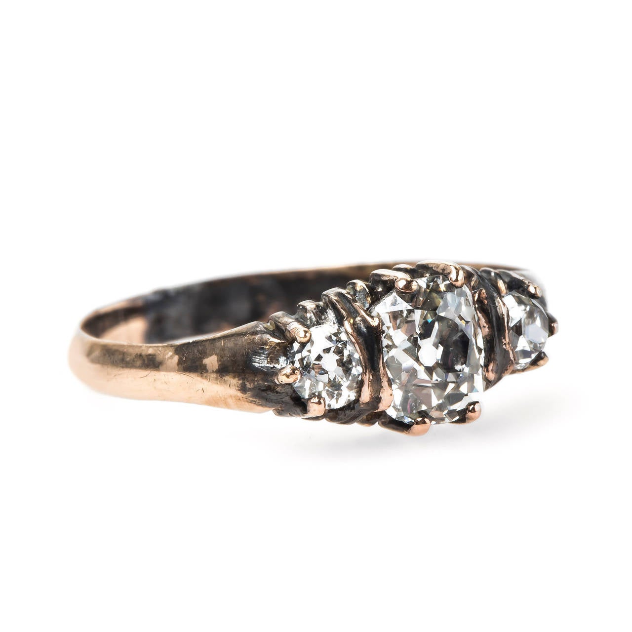 Elysian Park is a fabulous authentic Victorian era (circa 1880) 14k rose gold engagement ring featuring a winning three stone combination of diamonds. This unusual ring centers a 0.78ct EGL certified Old Mine Brilliant Cut diamond graded J color and