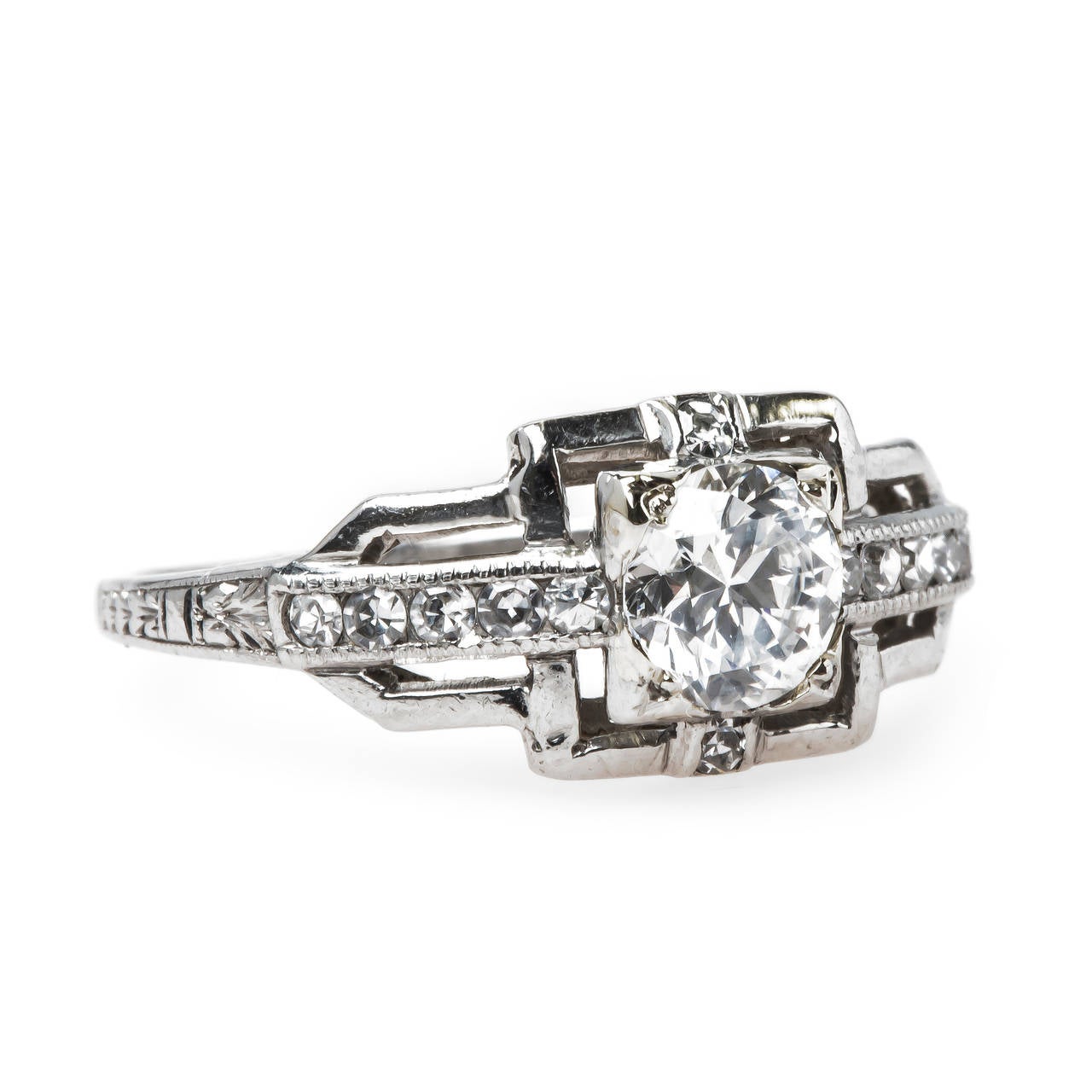 Colfax is the epitome of classic Art Deco (circa 1925) design, made in platinum and centering a 0.64ct EGL certified Round Brilliant Cut diamond graded E color and VS1 clarity. A simple row of ten Single Cut diamonds totaling approximately 0.10ct