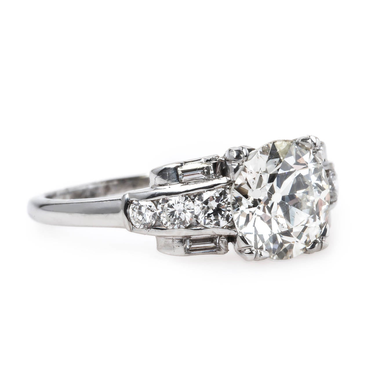 Royalston is an incredible authentic Mid-Century (circa 1950) platinum engagement ring centering a 1.55ct EGL certified Old European Cut diamond graded J color and SI1 clarity. This fabulous ring is flanked by a line of six tapering Round Brilliant