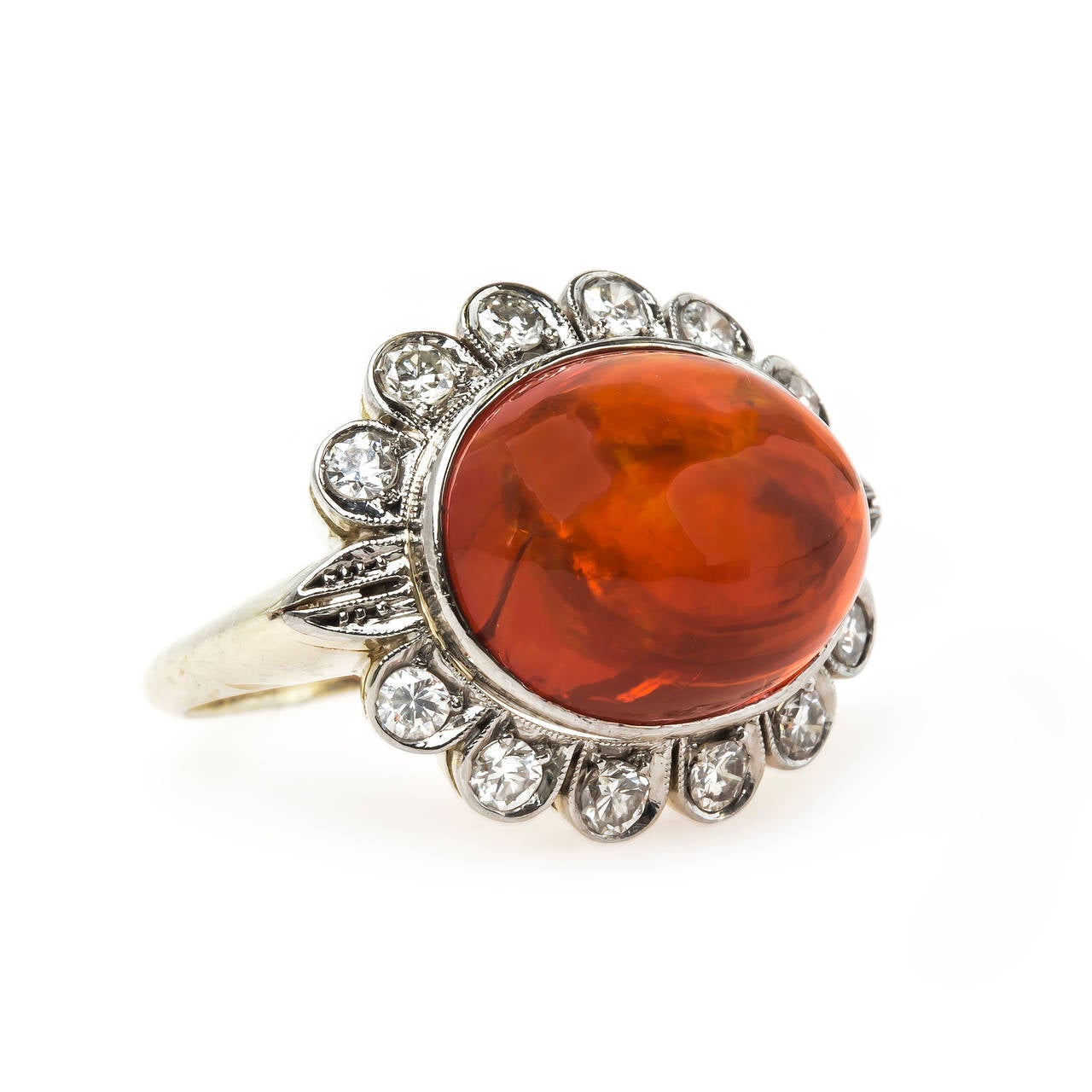 Copper Beach is an over-the-top authentic Retro era (circa 1945) platinum topped 14k yellow gold cocktail halo ring centering a large Oval Cabochon fire opal weighing exactly 6.80cts and surrounded twelve Round Brilliant Cut diamonds totaling
