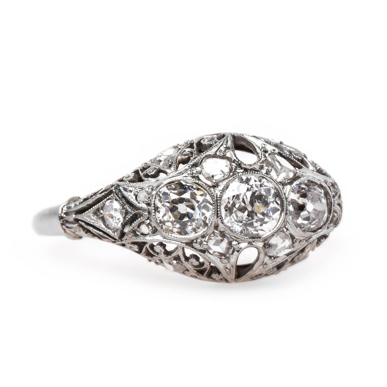Silver Quill is an elegant and thoughtfully designed vintage Edwardian era (circa 1915) platinum three-stone engagement ring. The ring centers three Old Mine Cut diamonds totaling approximately 0.70ct in weight, surrounded by eight artistically